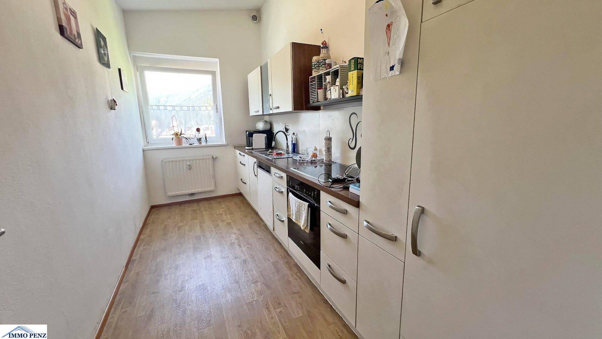 Funktionale Küche mit hellen Schränken, integrierten Geräten und Fenster für Tageslicht.