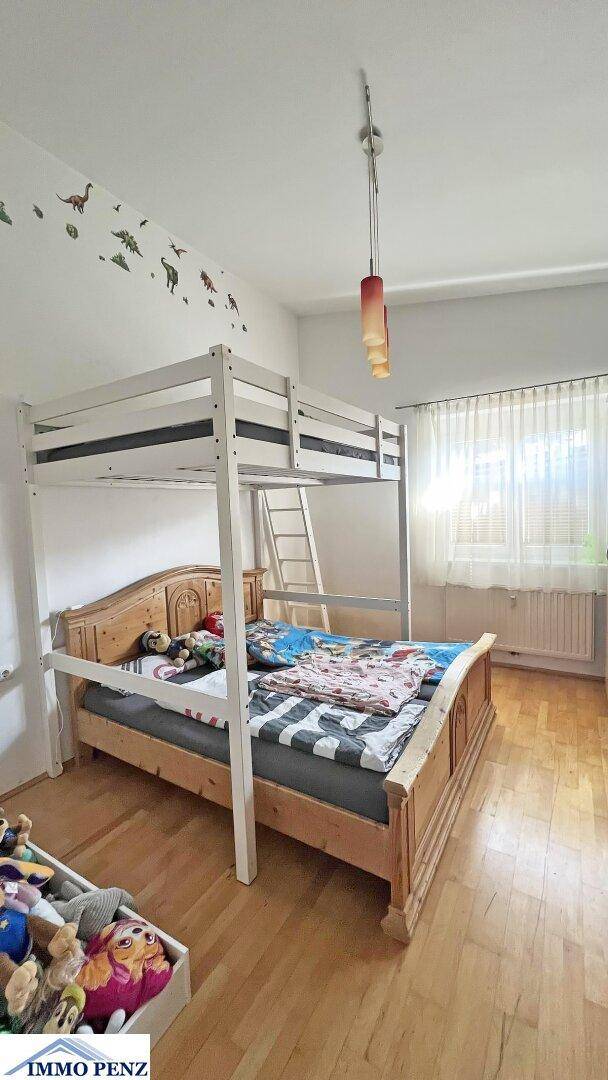 Helles Kinderzimmer mit Etagenbett, Holzboden und Fenster für natürliche Belichtung.