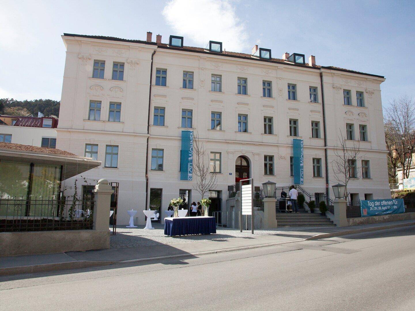 Die Vorderseite eines historischen Gebäudes, geschmückt für eine Veranstaltung mit blauen Bannern und Tischen.