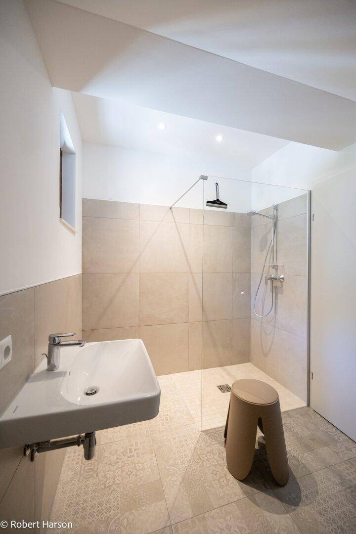 Modernes Badezimmer mit begehbarer Dusche, Fliesenboden und kleinem Fenster.