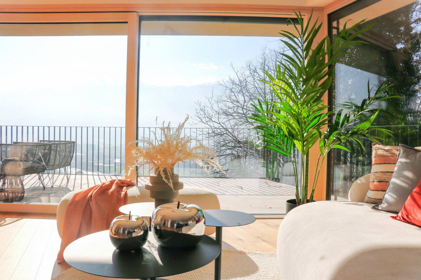 Lichtdurchflutetes Wohnzimmer mit moderner Einrichtung, Holzboden und weitem Ausblick.