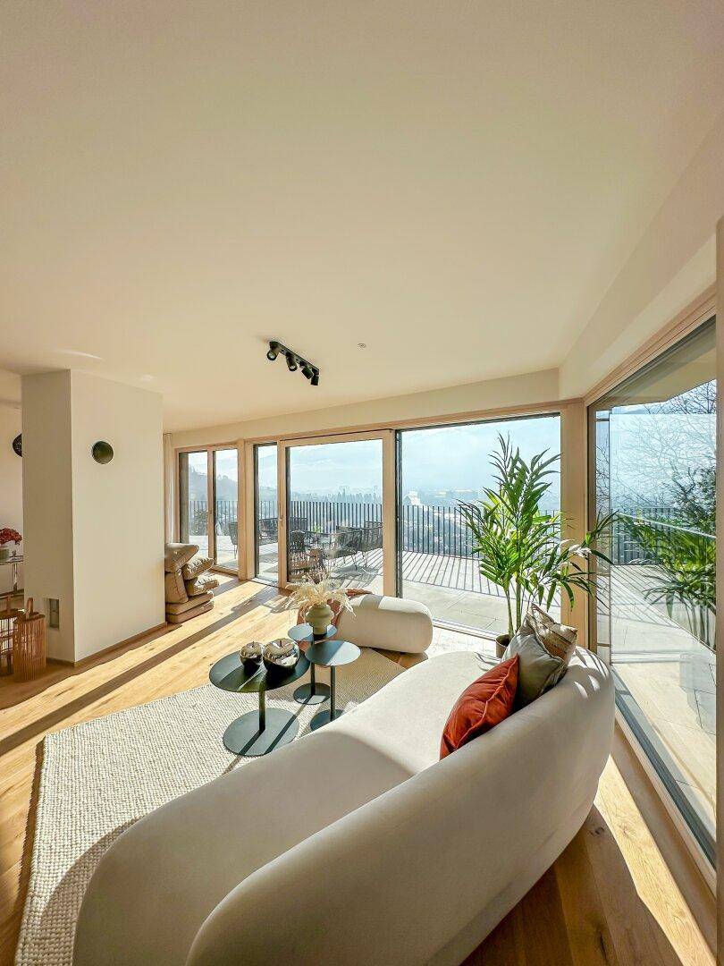 Helles Wohnzimmer mit Panoramablick über die Stadt und die Berge von der Terrasse aus.