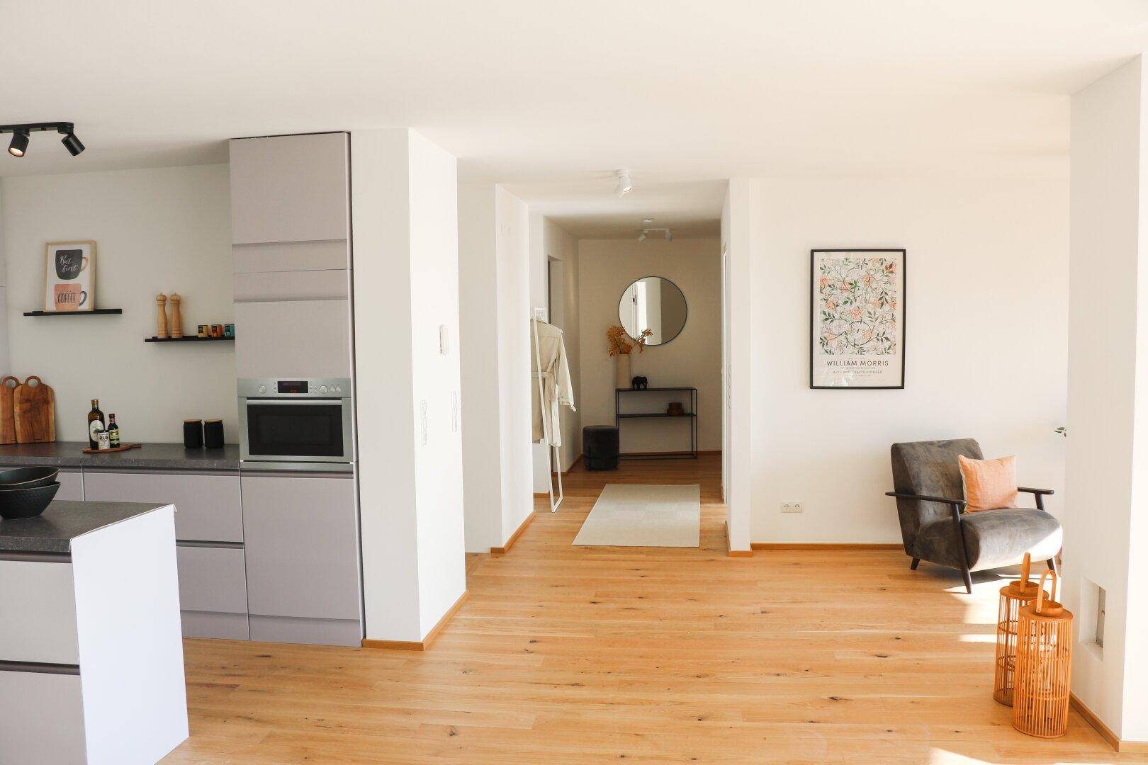 Heller Flur mit Holzboden, modernem Dekor und Zugang zu Küche und Wohnbereich.