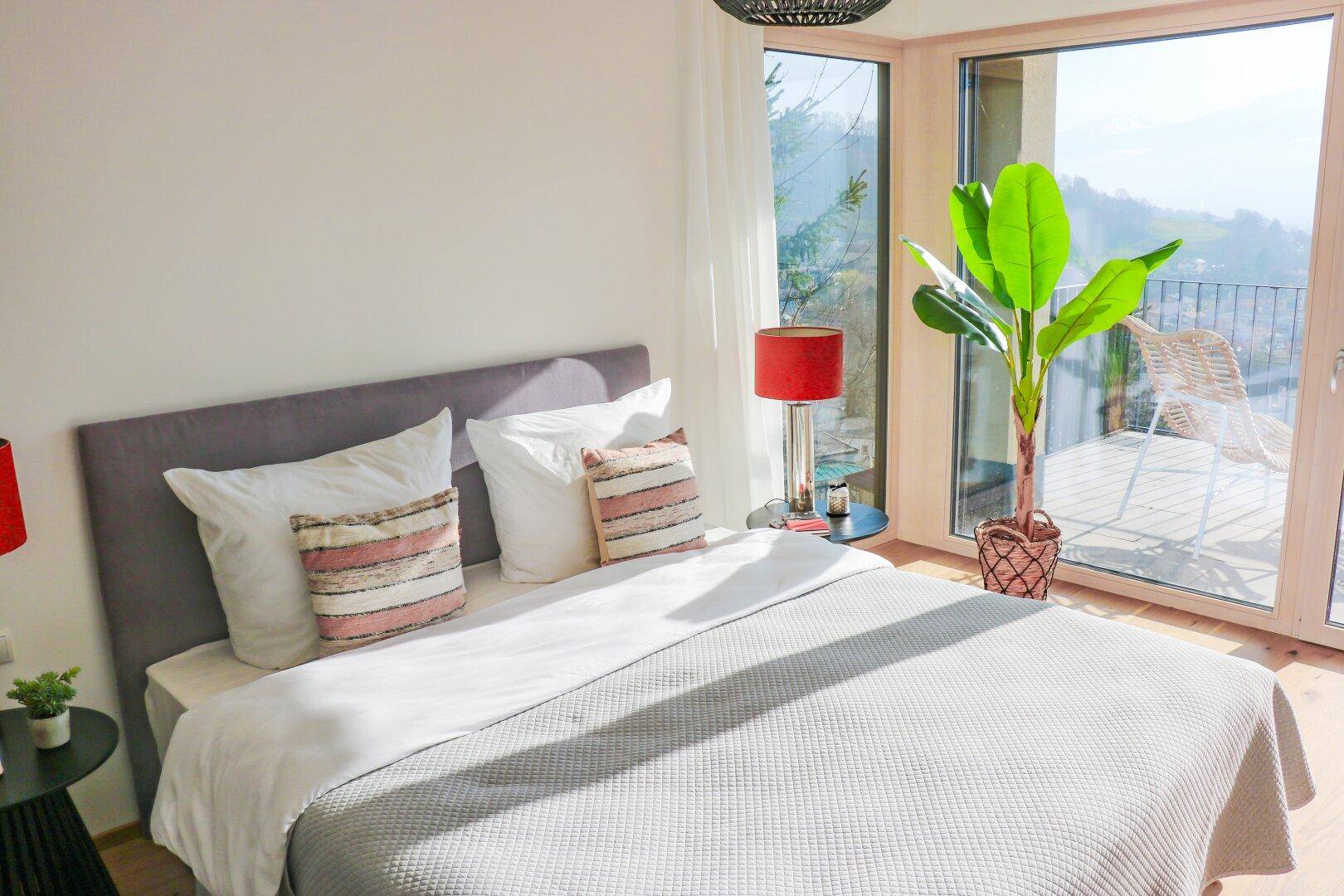 Schlafzimmer mit Doppelbett, Holzboden und großen Fenstern mit weitem Ausblick.