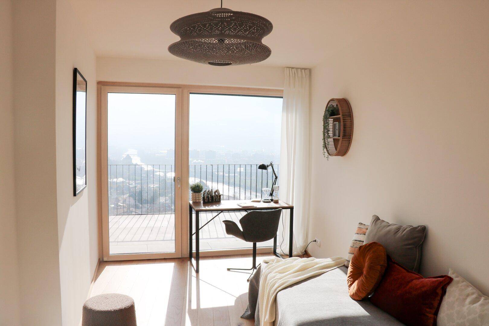 Helles Arbeitszimmer mit Schreibtisch, Stuhl und weitem Blick durch große Fenster.