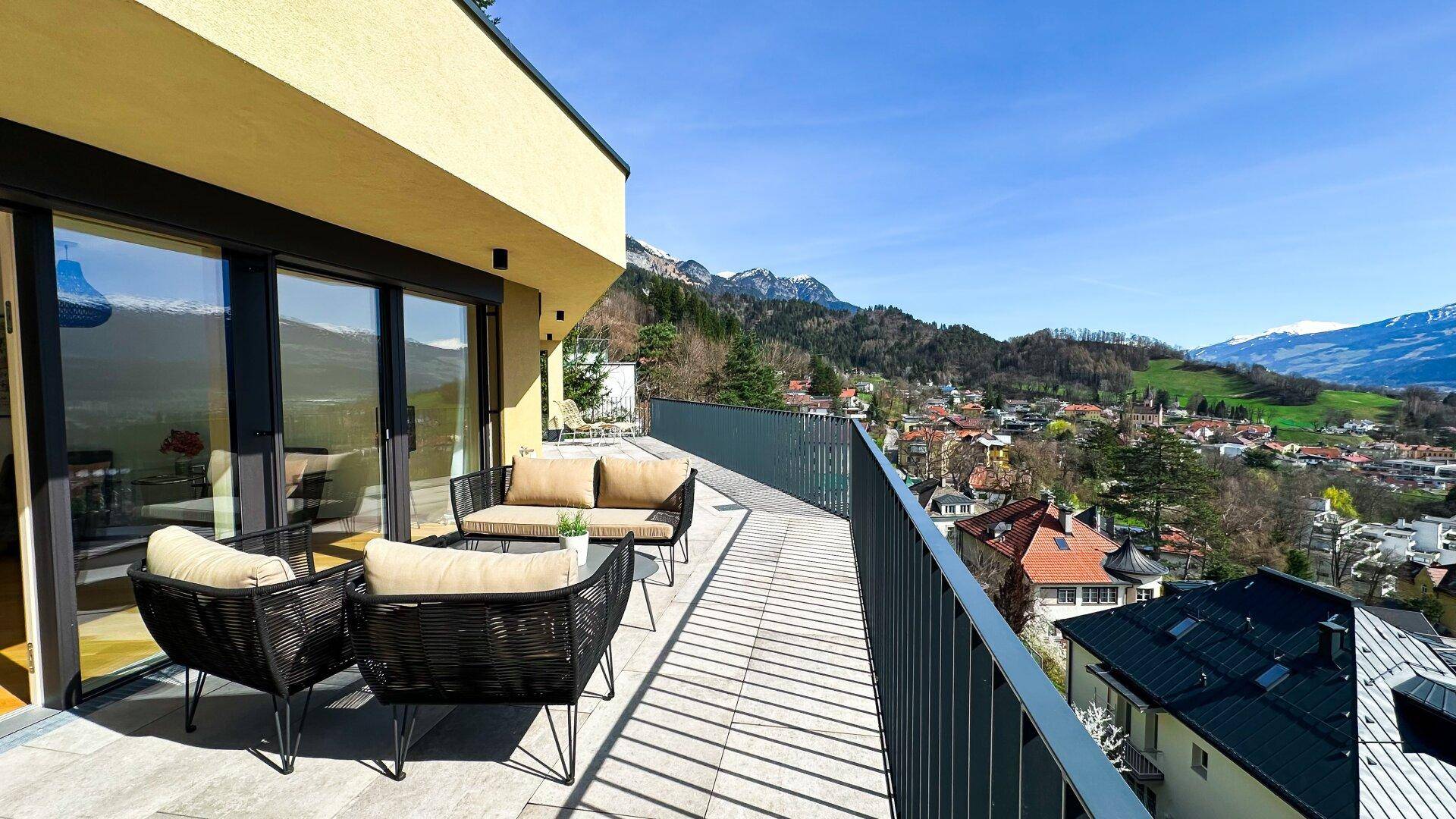 Geräumige Terrasse mit Sitzgelegenheiten und weitem Blick über die Stadt und die Berge.