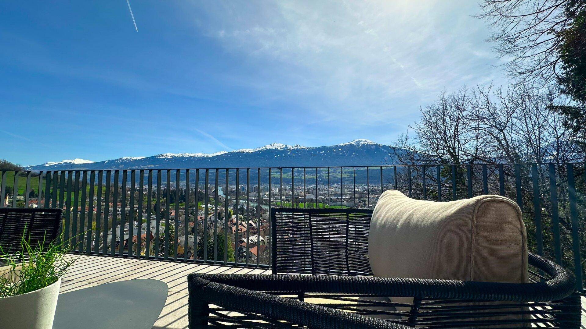 Gemütlicher Sitzbereich auf der Terrasse mit Panoramablick auf die schneebedeckten Berge.