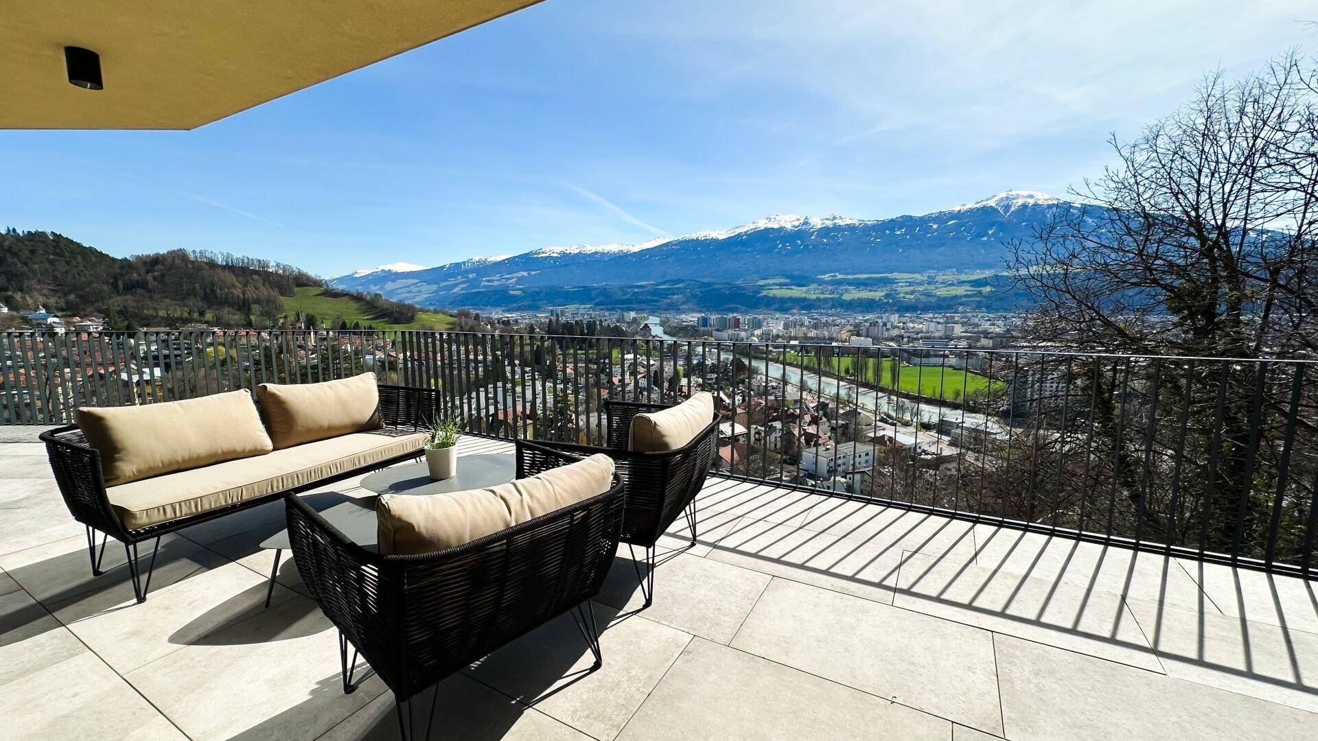 Große Sonnenterrasse mit bequemen Gartenmöbeln und atemberaubendem Berg- und Stadtblick.
