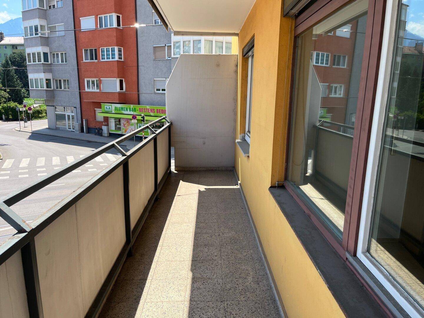 Schmaler Balkon mit Fliesenboden und Blick auf die Straße und umliegende Gebäude.