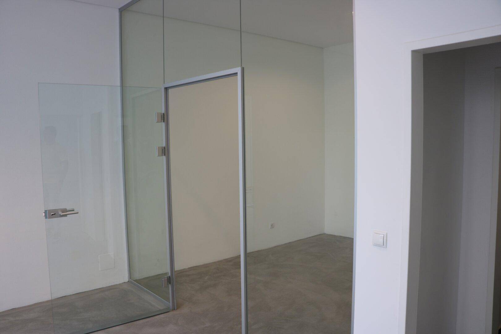 Moderner, leerer Gewerberaum mit Glaswänden und einem hellen, minimalistischen Design.