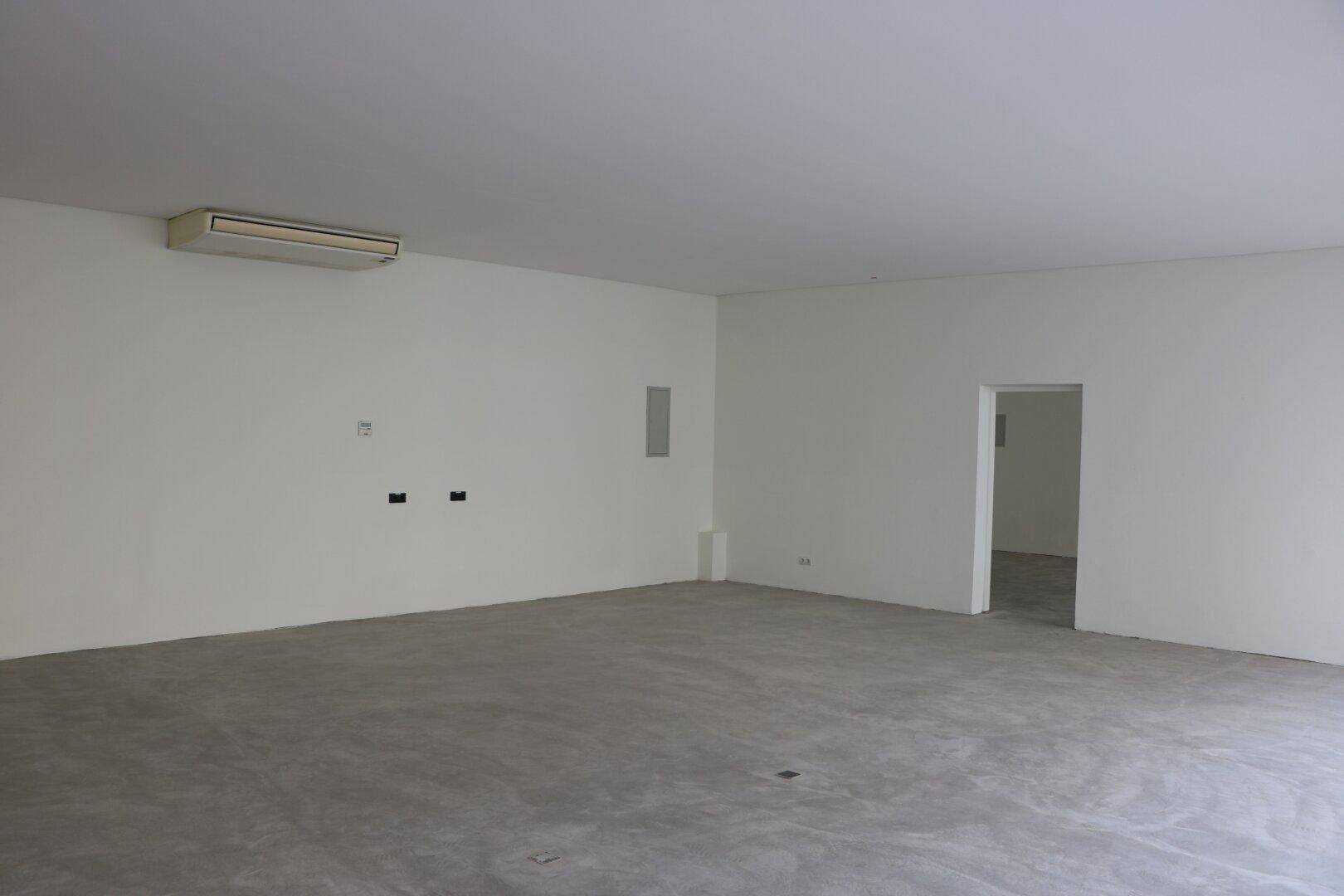 Geräumiger, leerer Raum mit weißen Wänden und einem Klimagerät für angenehmes Raumklima.