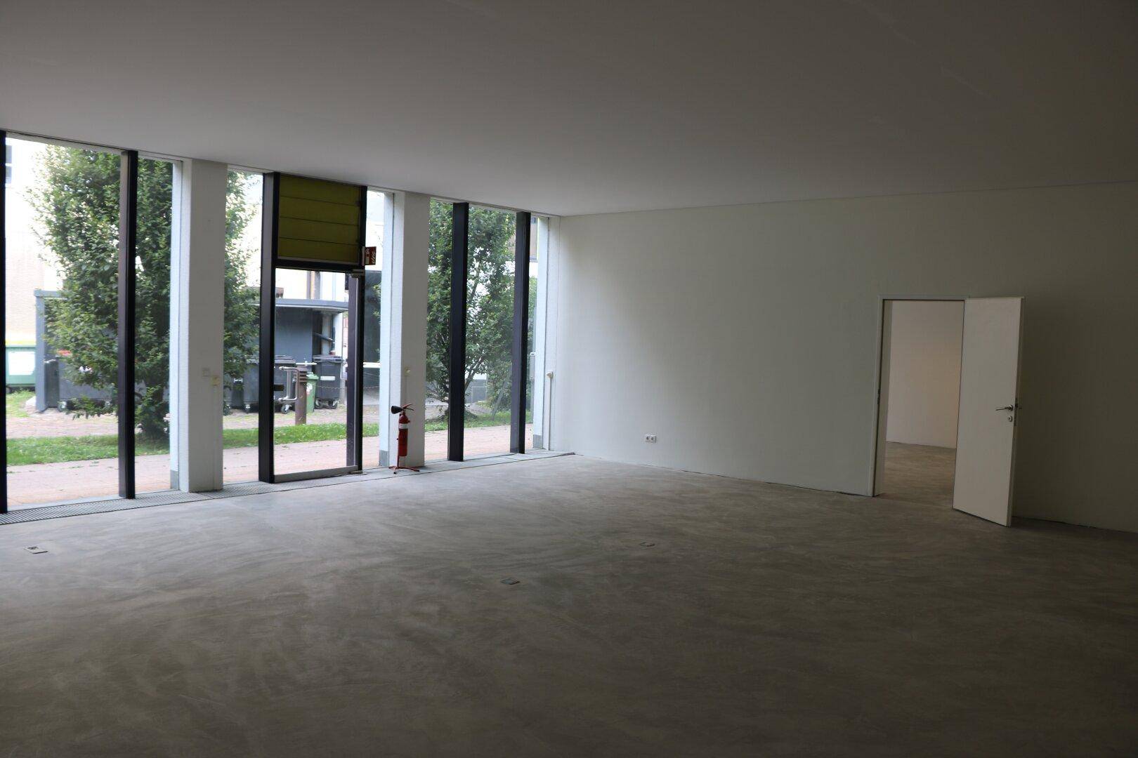 Großer, heller Gewerberaum mit durchgehenden Fenstern und viel Tageslicht.