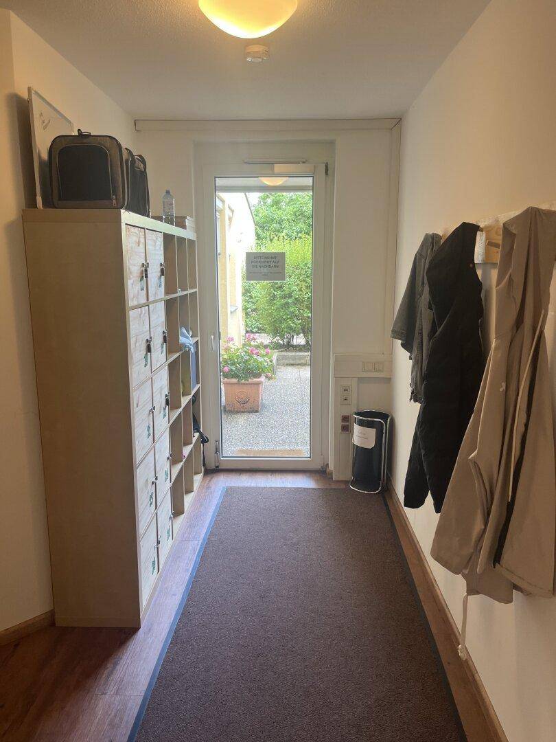 Heller Eingangsbereich mit Garderobe, Schuhregal und Blick nach draußen.