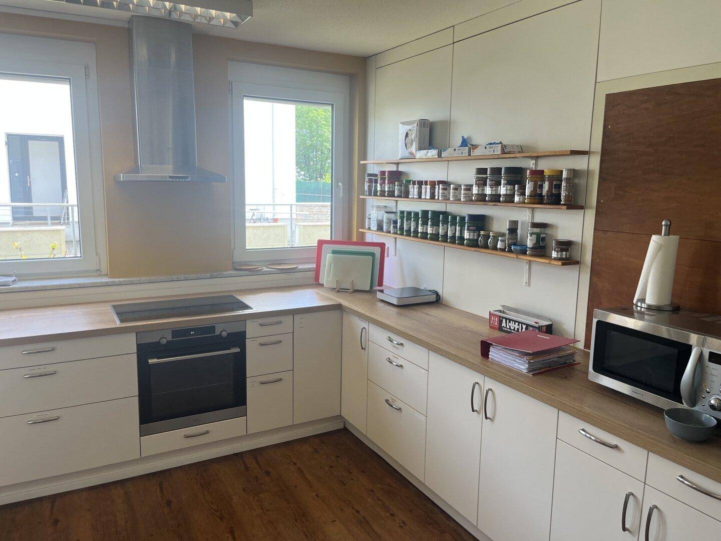 Moderne Einbauküche mit hellen Holz-Arbeitsplatten, Induktionskochfeld und Backofen.