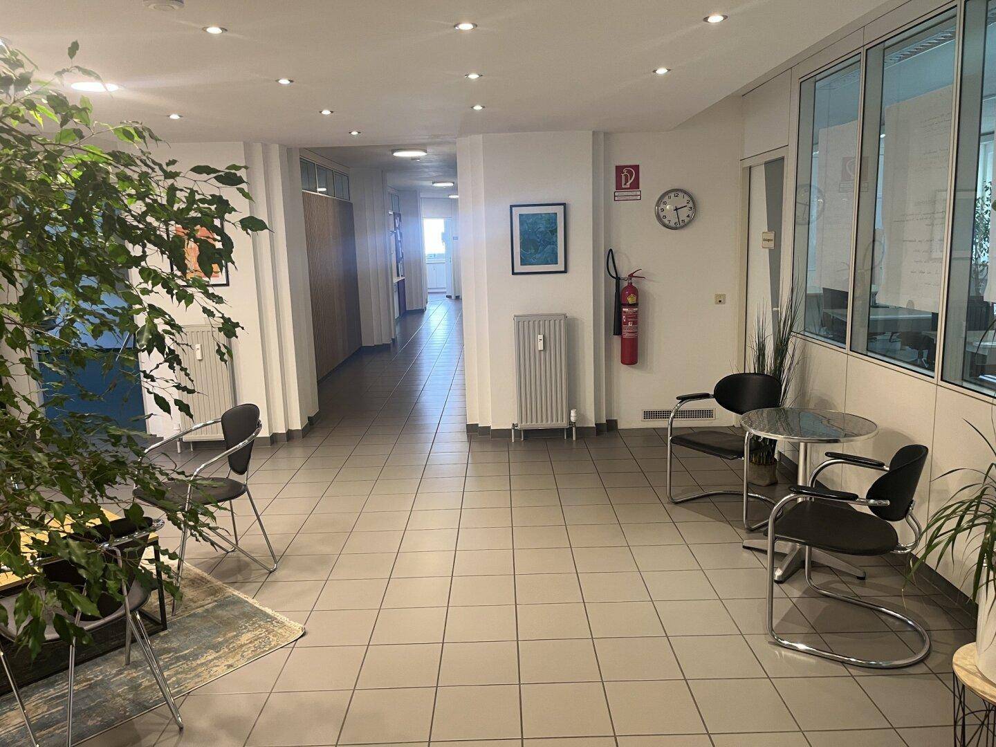 Langer Flur mit Fliesenboden, Heizkörpern und Zugang zu verschiedenen Büroräumen.