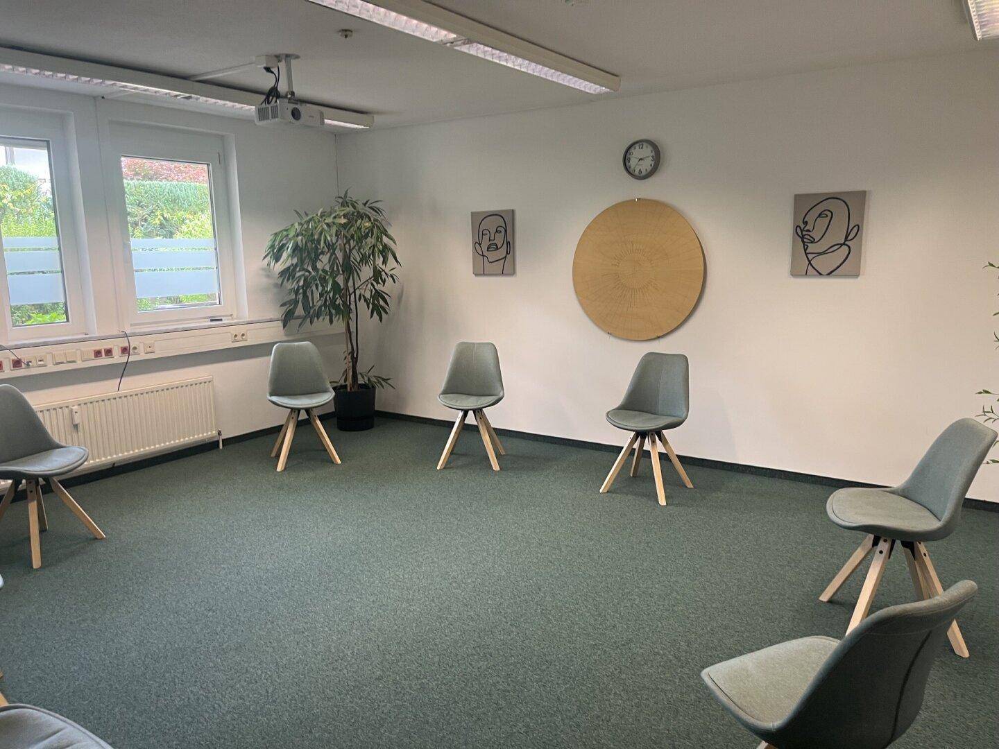 Besprechungsraum mit Teppichboden, modernen Stühlen und dekorativen Wandbildern.