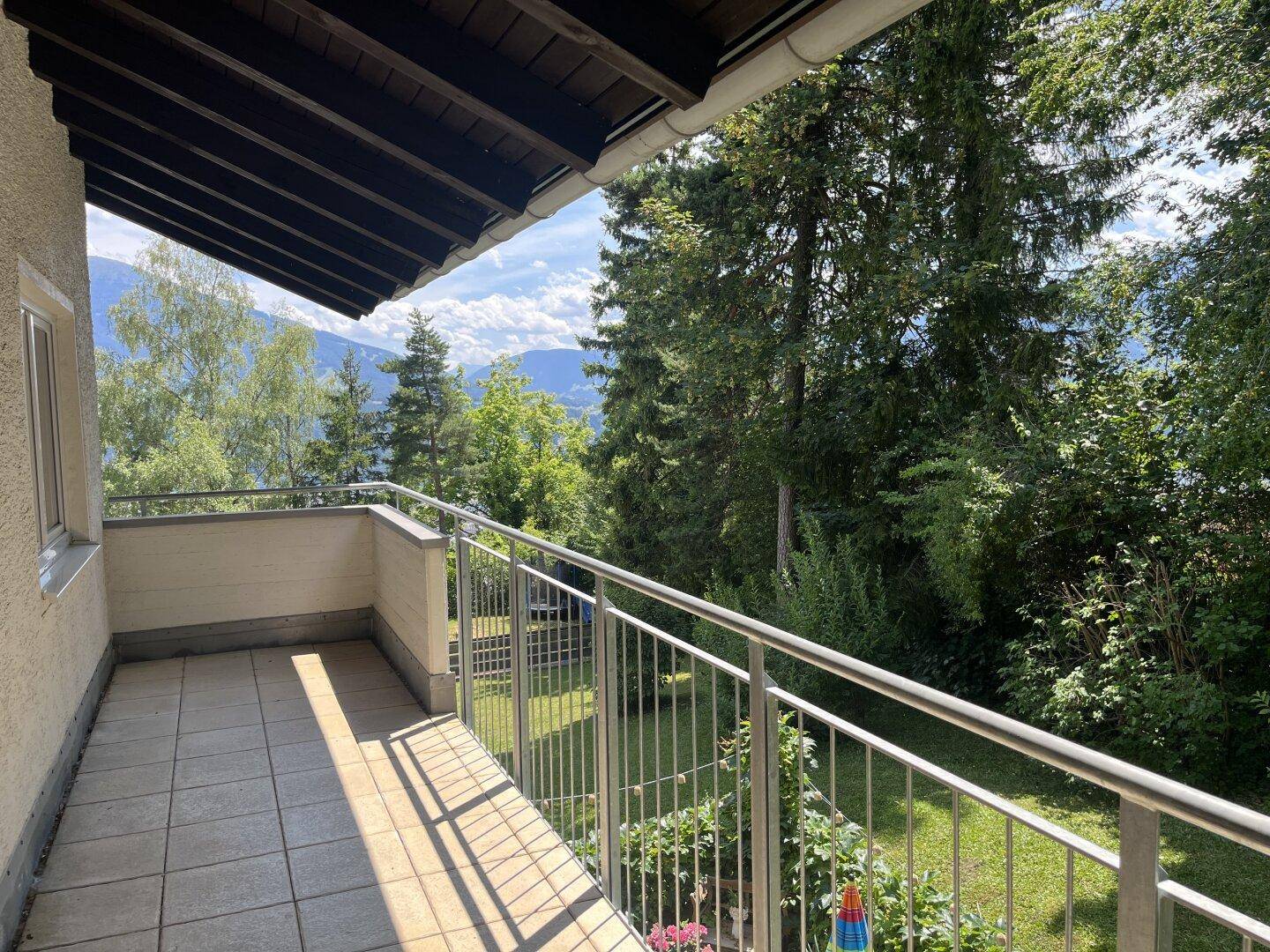 Langer Balkon mit Fliesenboden und weitem Blick auf Berge und grüne Landschaft.