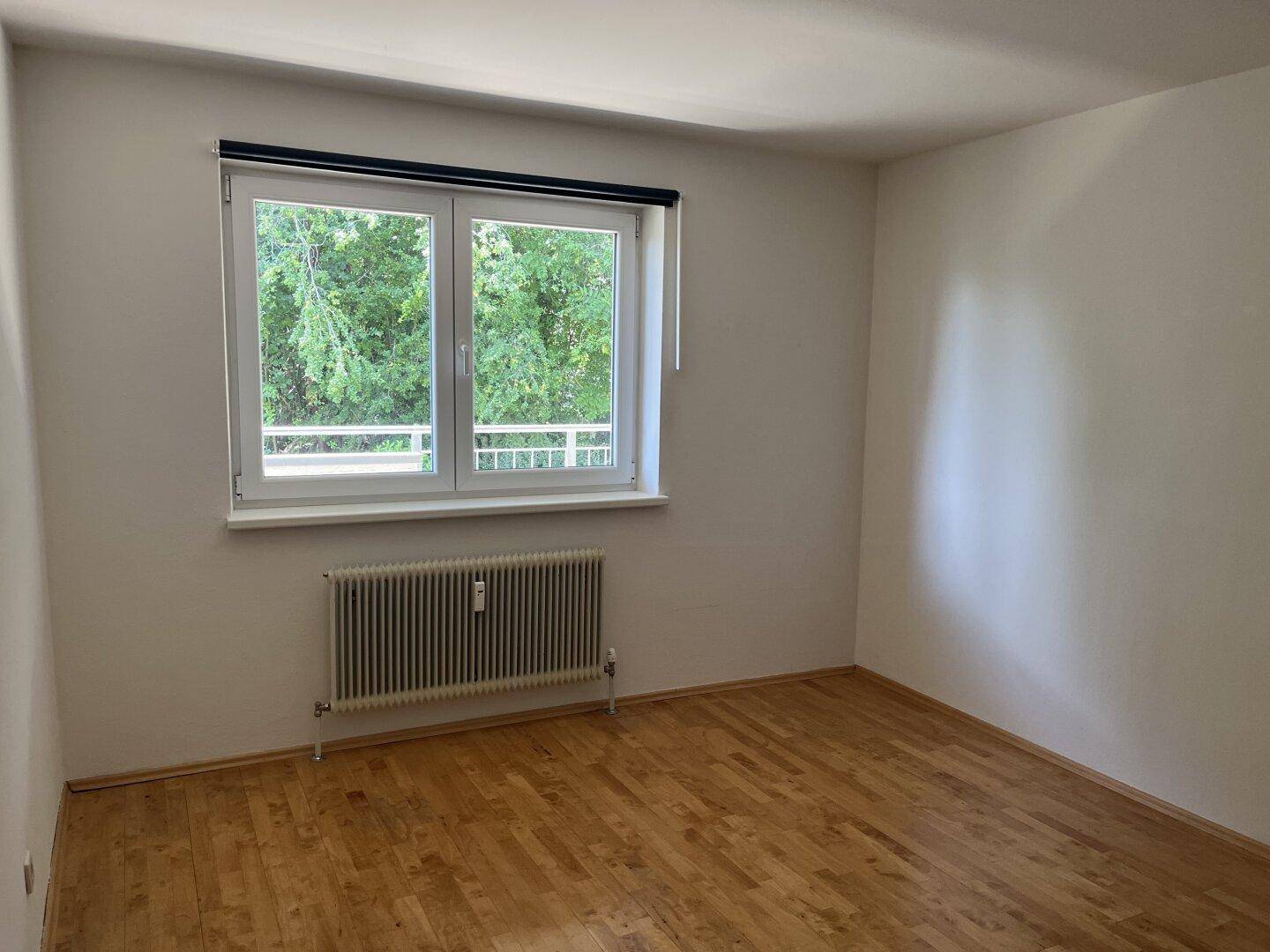 Geräumiges Zimmer mit Holzboden und Fenster, das viel Tageslicht hereinlässt.
