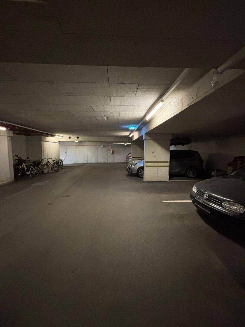 Geräumige Tiefgarage mit mehreren Stellplätzen, Fahrrädern und Beleuchtung.