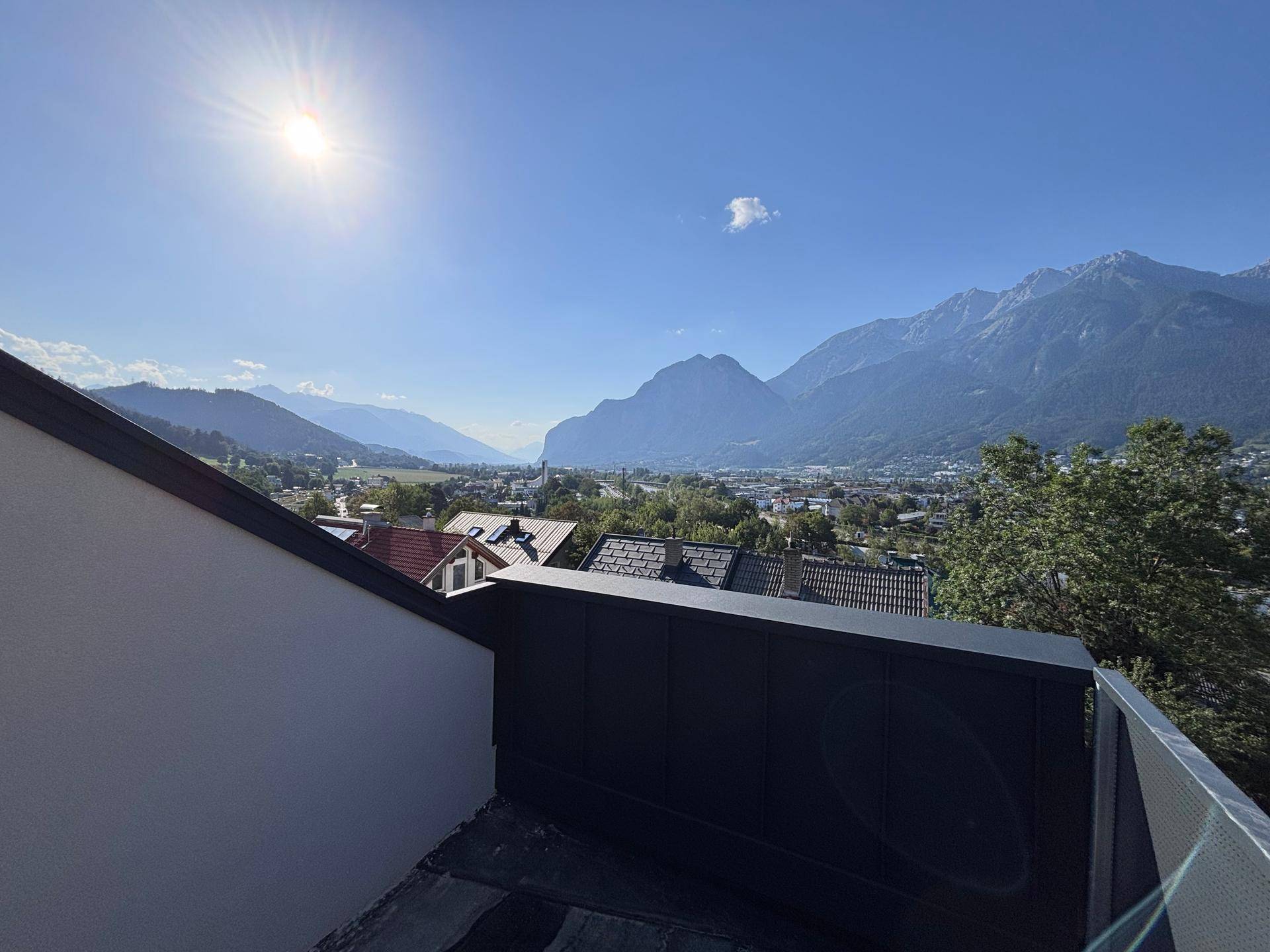 Sonniger Balkon mit weitem Blick über die Stadt und die umliegende Berglandschaft.