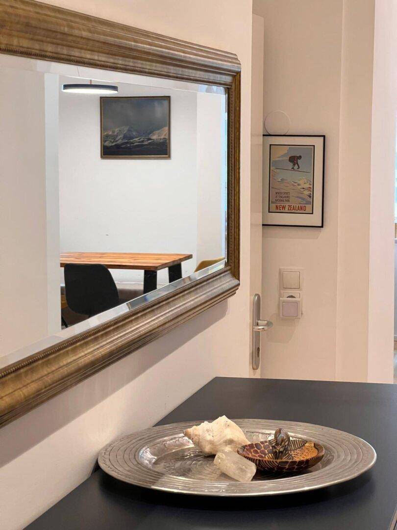 Eingangsbereich mit antikem Spiegel, der einen Essbereich mit Holztisch reflektiert.