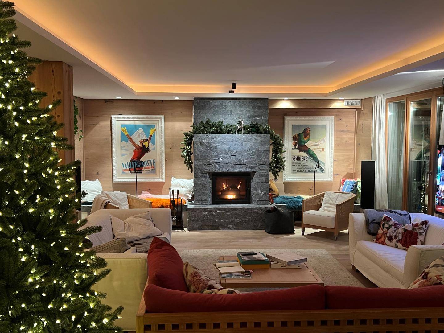 Gemütliches Wohnzimmer mit Kamin, Weihnachtsbaum und indirekter Beleuchtung.