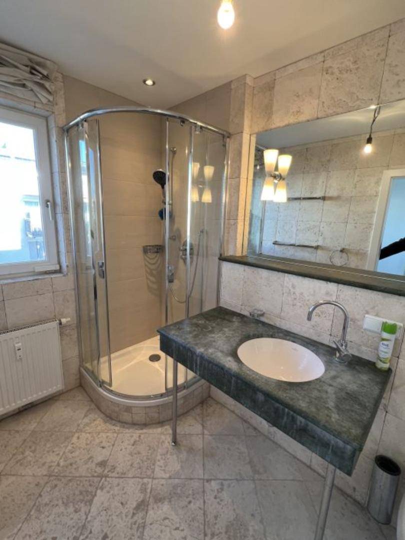 Badezimmer mit Eckduschkabine, Einzelwaschbecken und Fenster.
