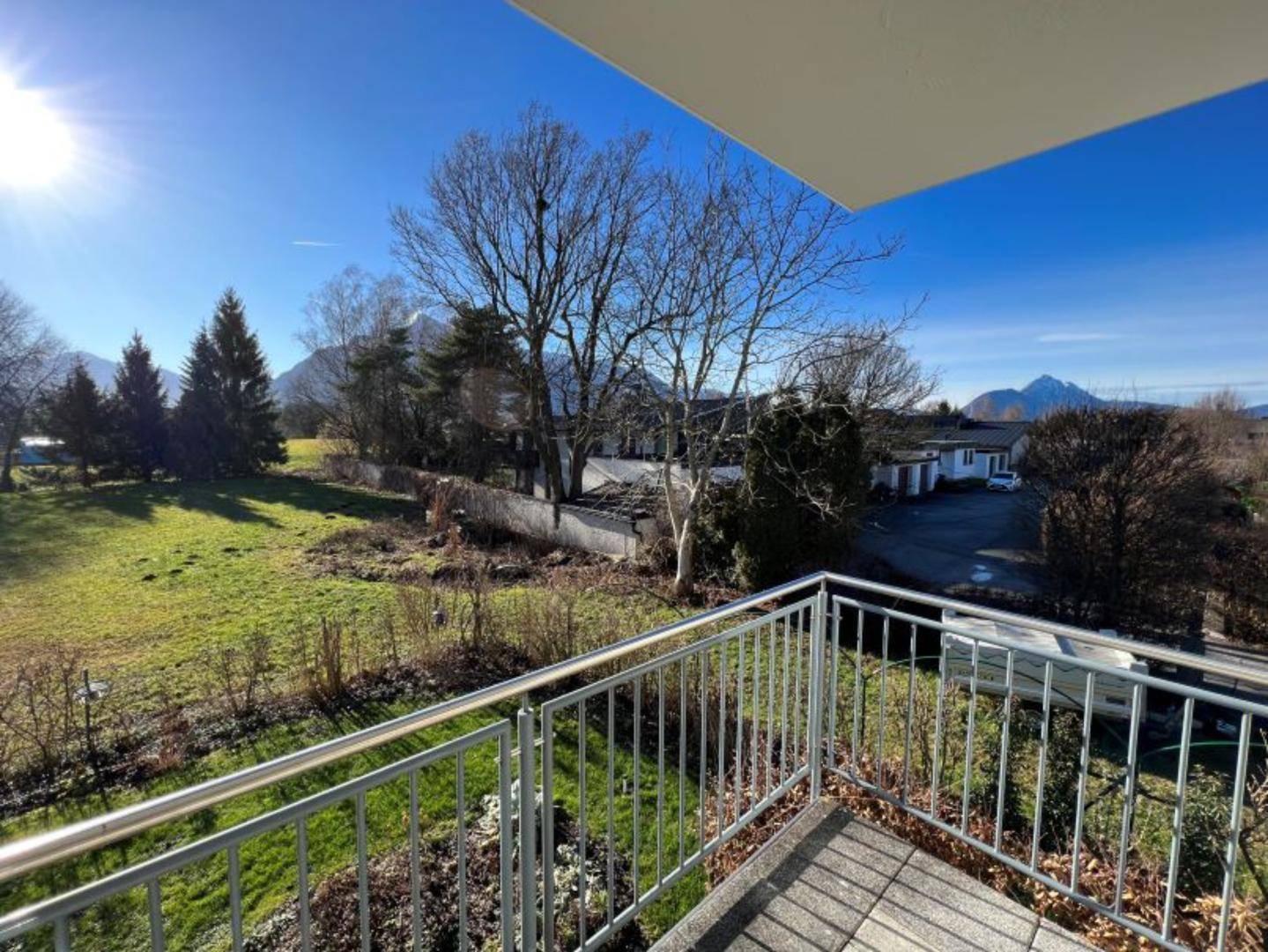 Heller Balkon mit Metallgeländer und Panoramablick auf die Natur und Berge.