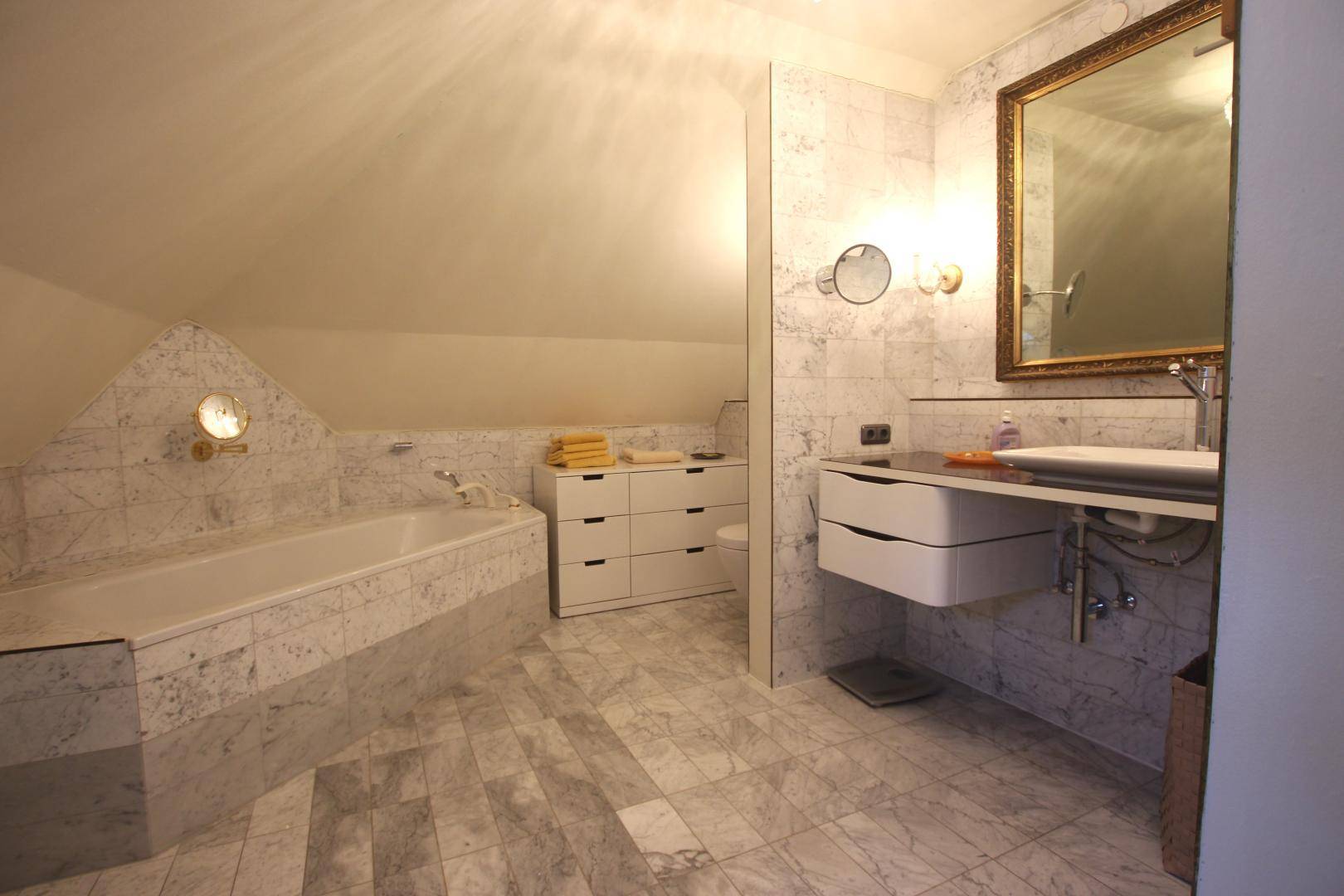 Elegantes Badezimmer mit Marmorfliesen, eingebauter Badewanne und modernem Waschtisch.