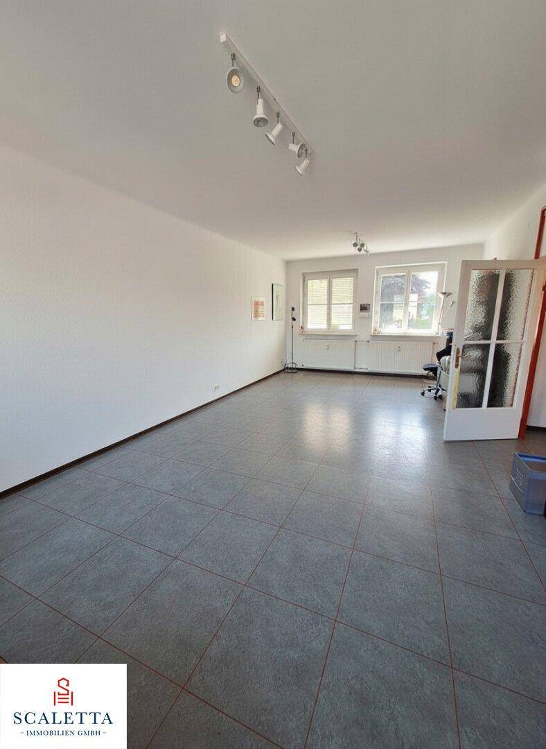 Geräumiger Büroraum mit grauen Fliesen und großen Fenstern, bereit zur individuellen Gestaltung.