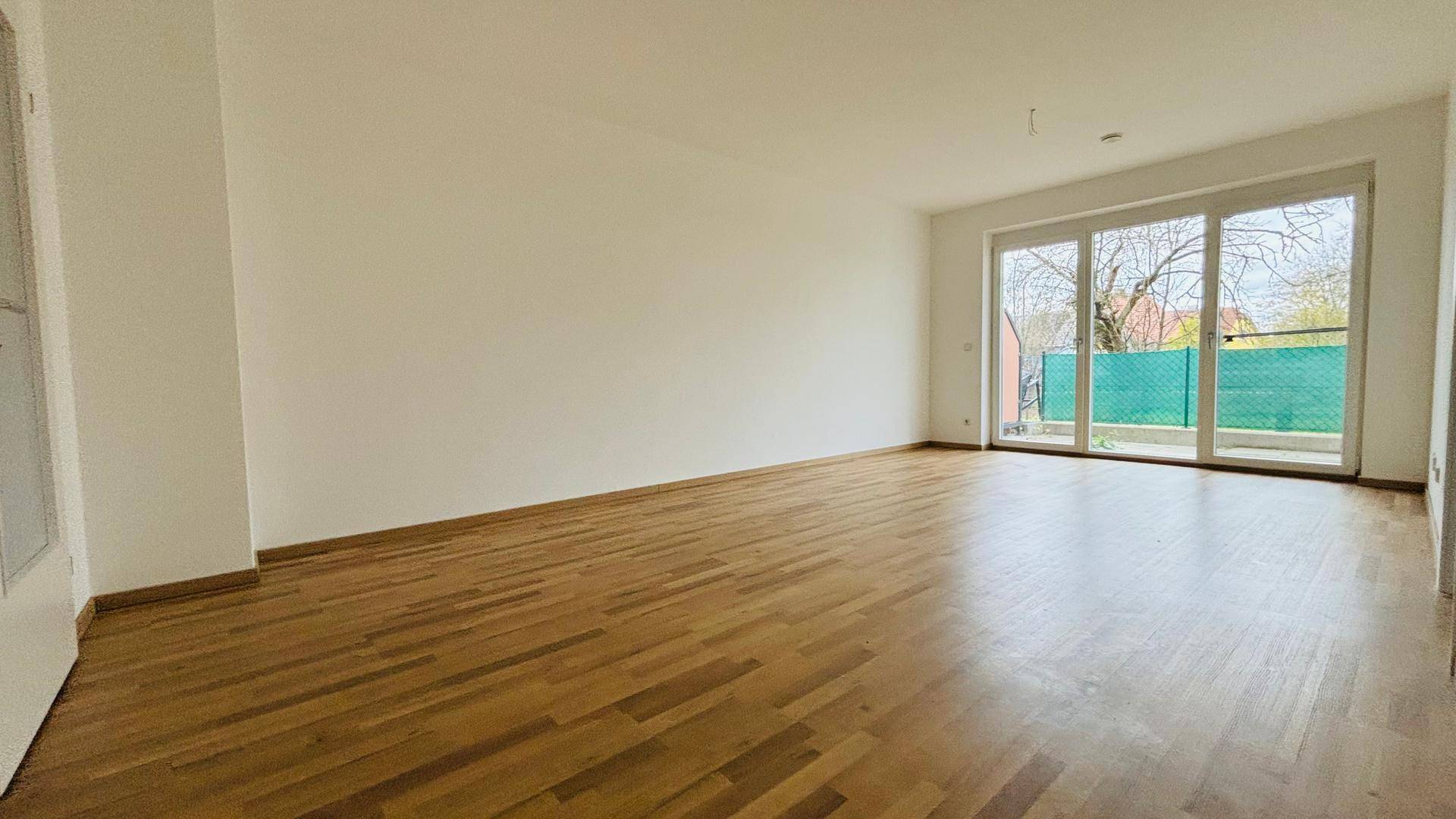 Lichtdurchflutetes Wohnzimmer mit großen Fenstern und Blick ins Grüne.