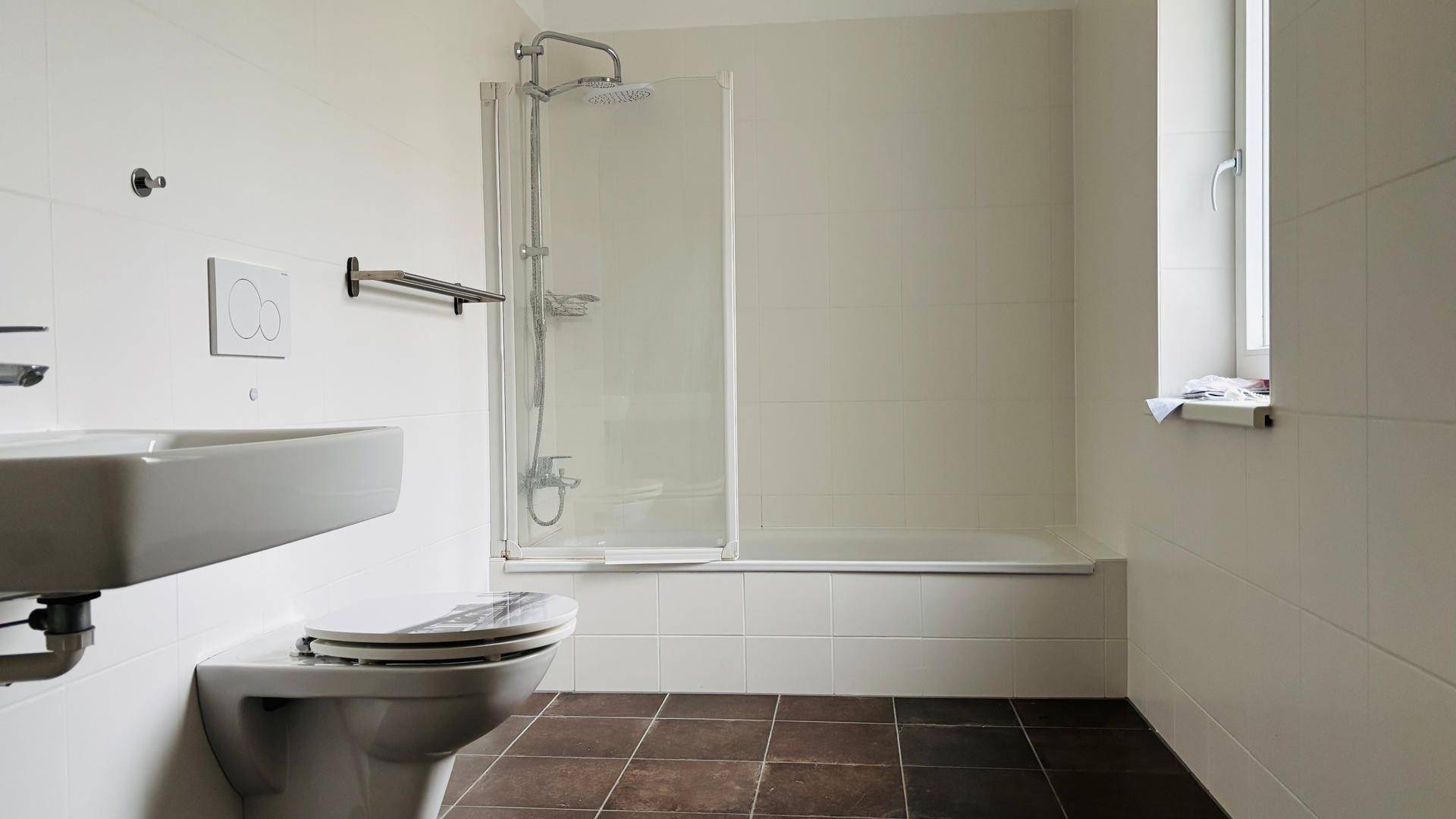 Modernes Badezimmer mit Badewanne, Dusche und Fenster für Tageslicht.