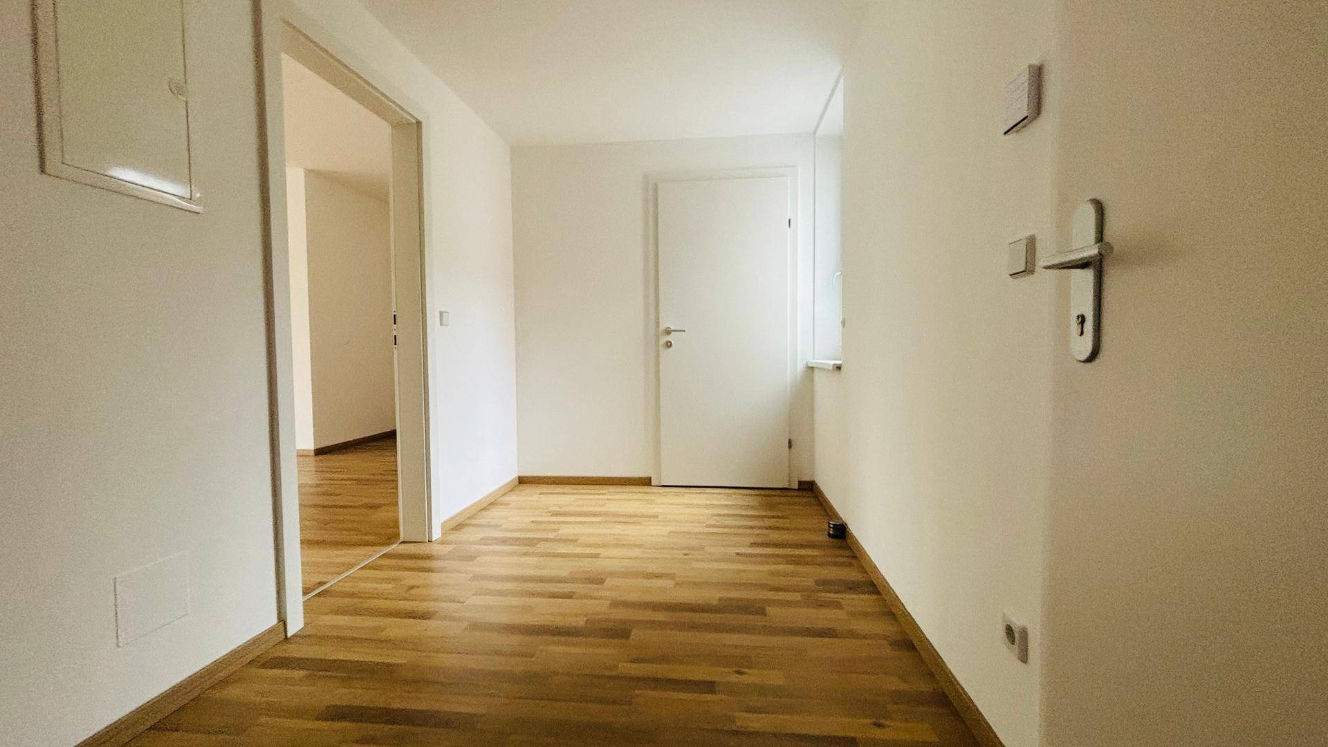 Heller Flur mit Parkettboden, der zu den verschiedenen Räumen führt.