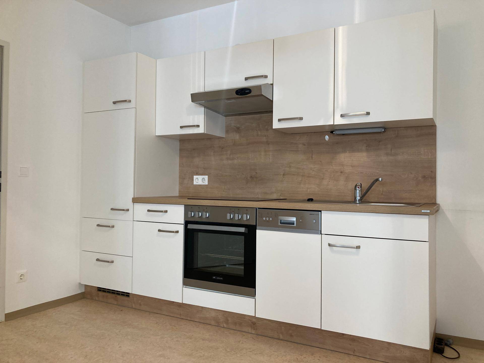 Moderne Einbauküche mit weißen Hochglanzfronten, Holzoptik-Rückwand und integrierten Geräten.