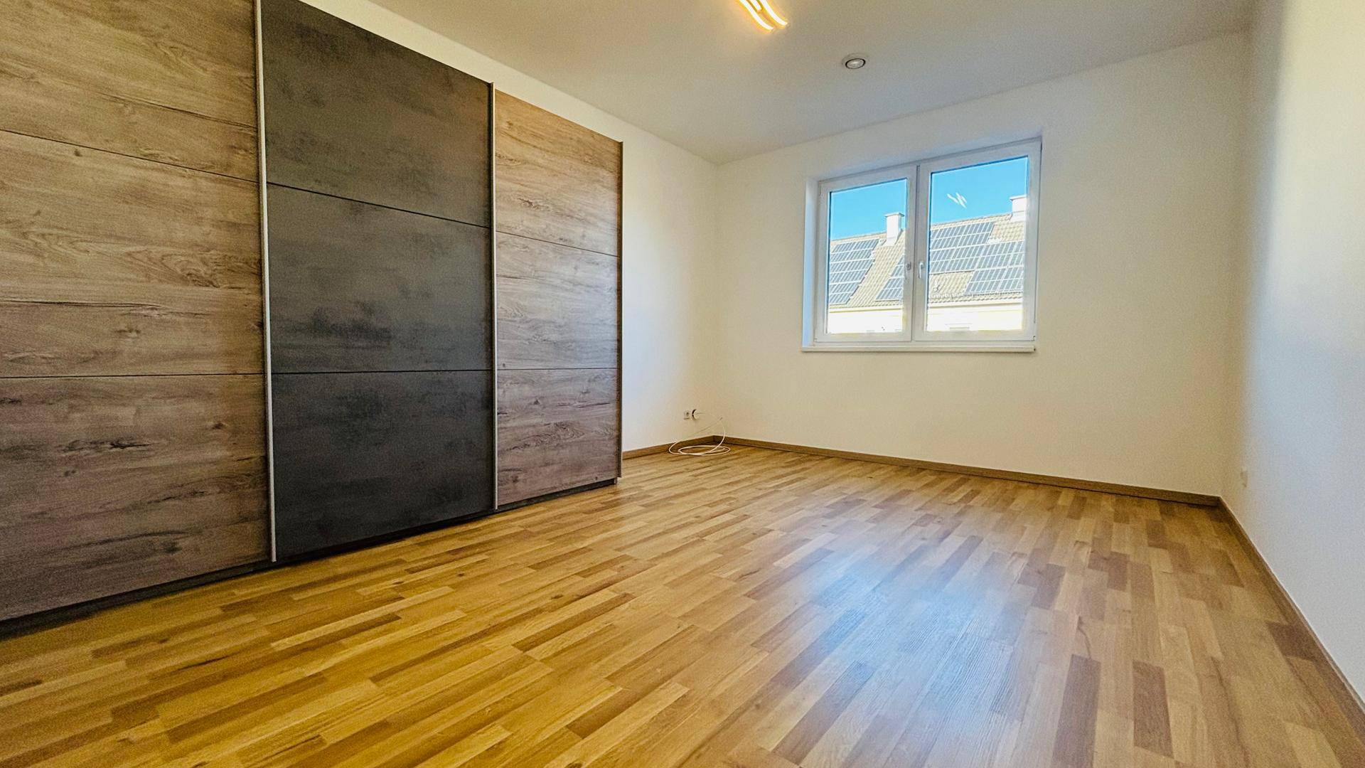 Helles Schlafzimmer mit Parkettboden und großem Einbauschrank, bietet viel Stauraum und Komfort.