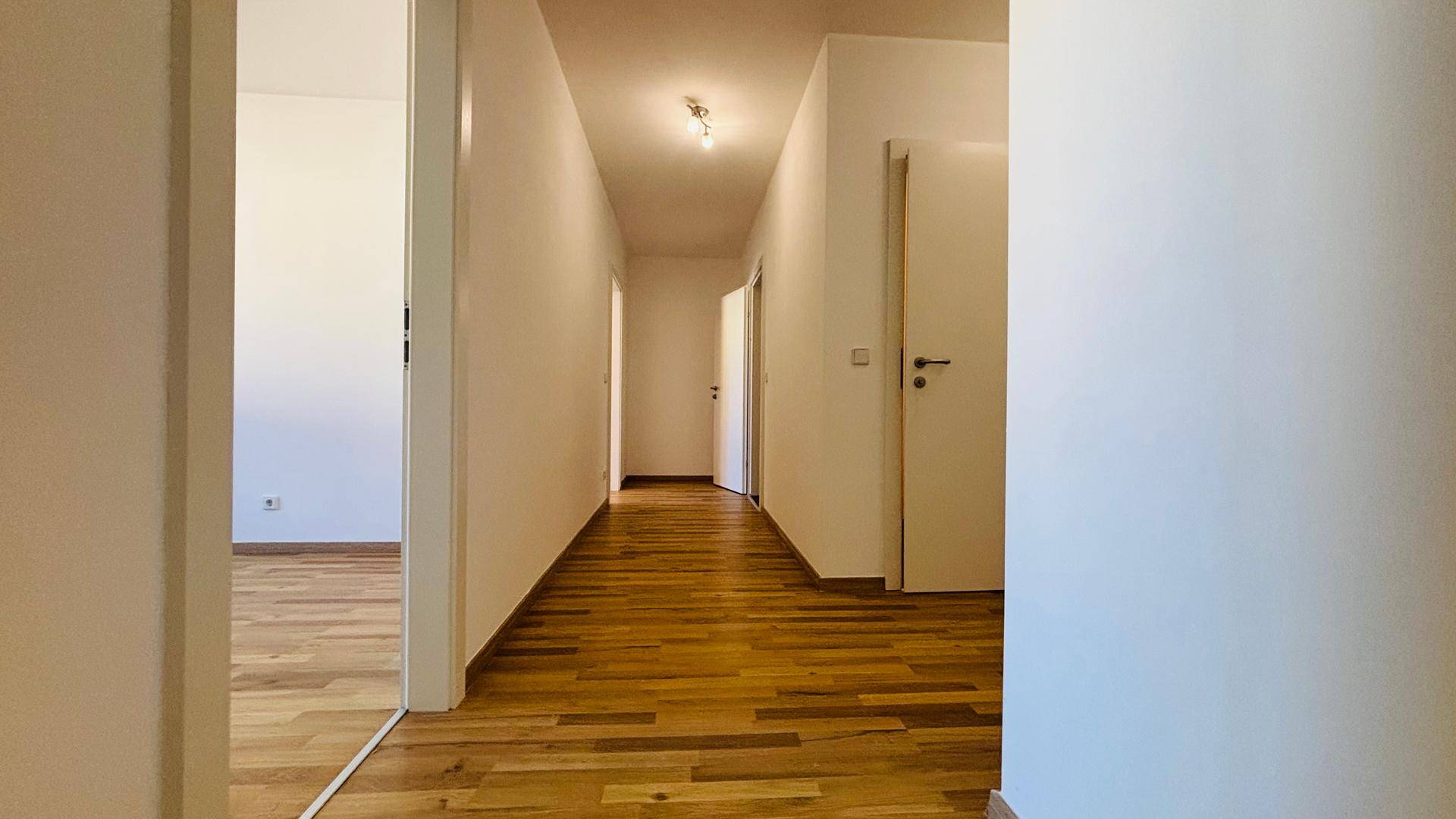Heller Flur mit Parkettboden, der zu den verschiedenen Räumen der Wohnung führt.