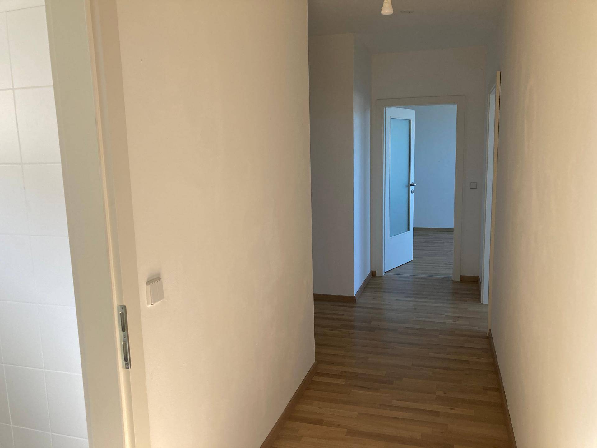 Heller Flur mit Parkettboden und Zugang zu mehreren Zimmern, der eine offene Atmosphäre schafft.