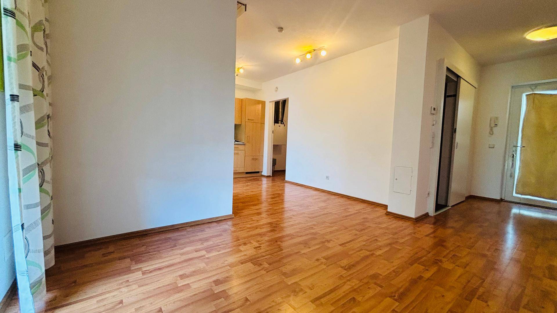 Offener Wohnbereich mit Holzboden und Blick auf die integrierte Küche, ideal für geselliges Beisammensein.