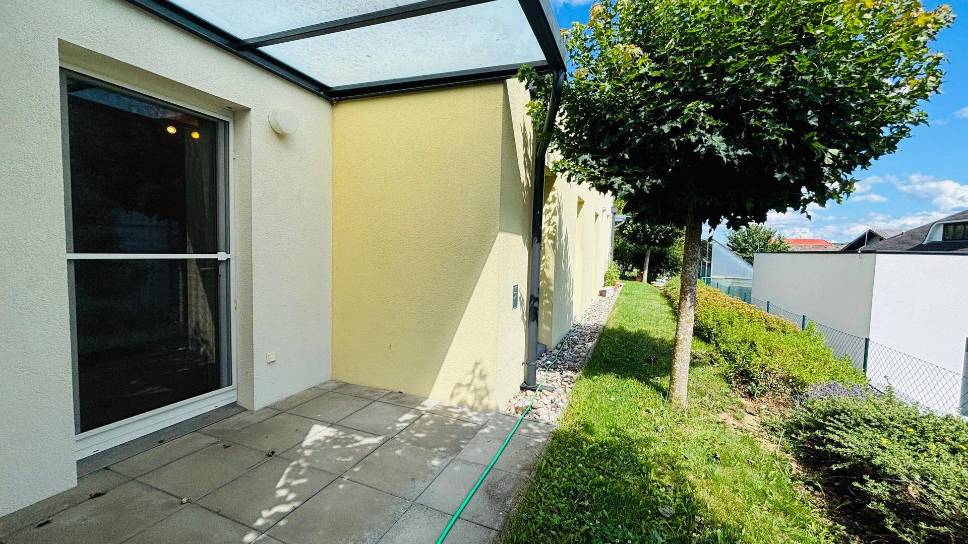 Sonnige Terrasse mit Glasüberdachung und direktem Zugang zum Garten.