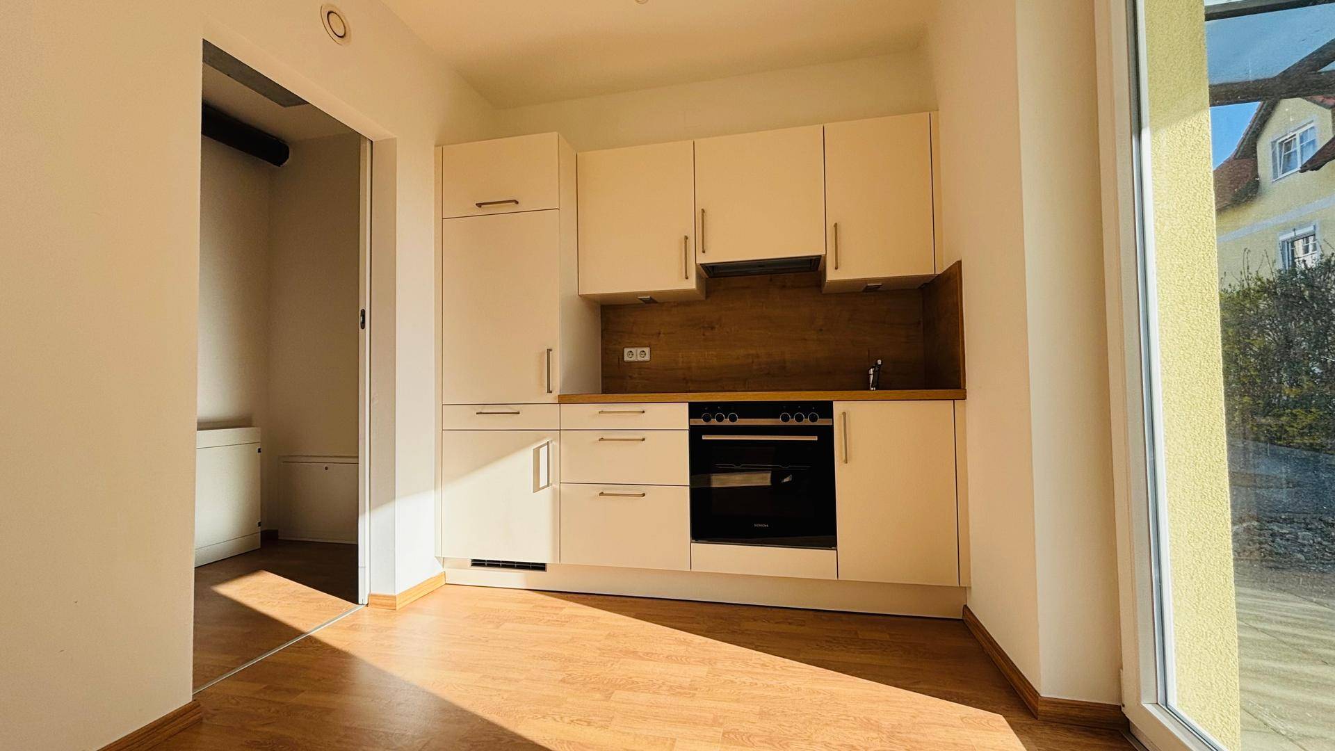 Moderne Einbauküche mit hellen Schränken, integrierten Geräten und Holzarbeitsplatte.