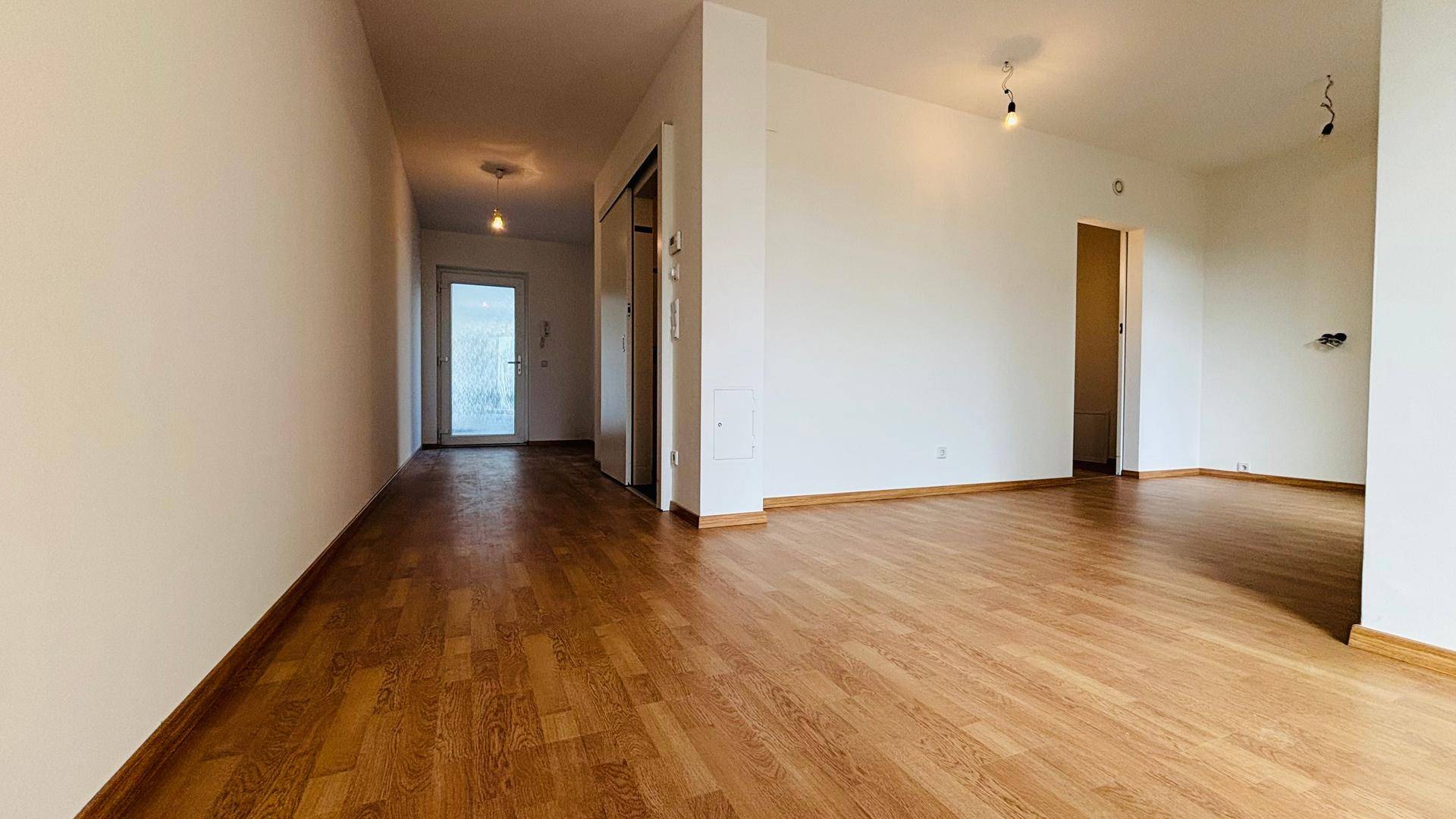 Langer Flur mit Holzboden, weißen Wänden und Türen zu verschiedenen Räumen.