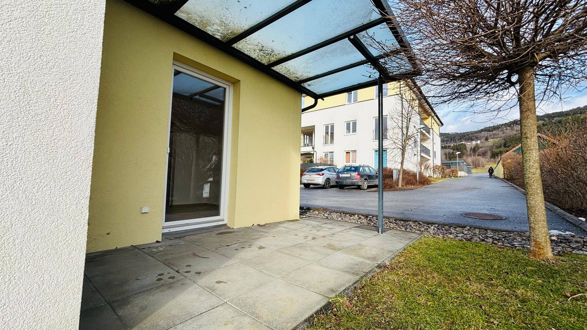 Gepflasterte Terrasse mit Überdachung und Blick auf die umliegenden Gebäude und die Straße.