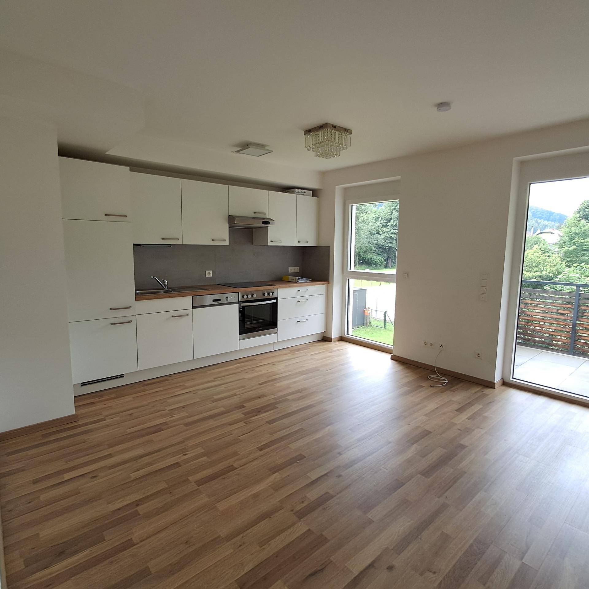 Offener Wohn- und Essbereich mit integrierter Küche und Zugang zum Balkon.