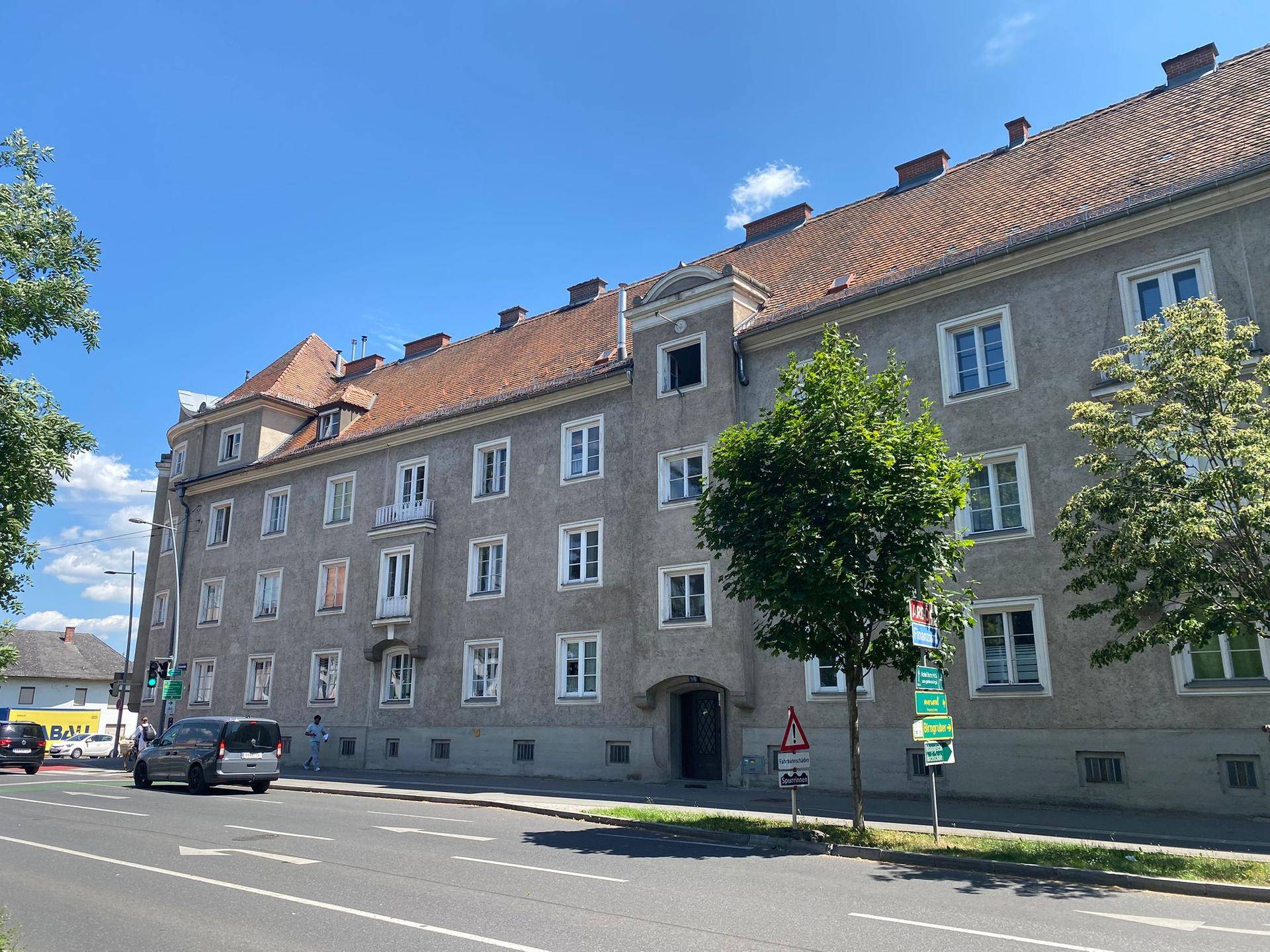 Wohngebäude mit traditioneller Architektur, vielen Fenstern und einem kleinen Balkon entlang einer städtischen Straße.