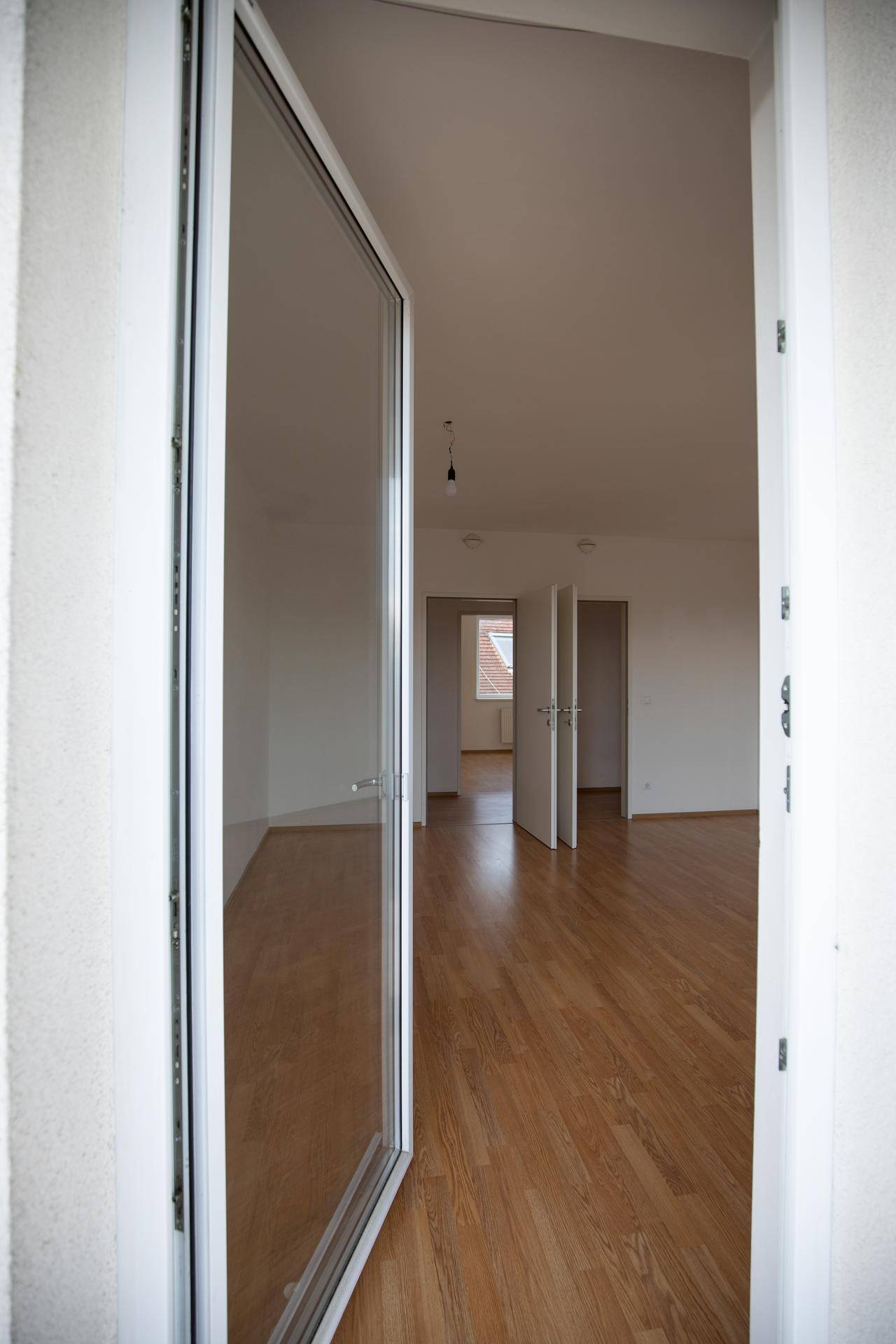 Eingangsbereich mit Holzboden, der zu weiteren hellen Räumen der Wohnung führt.