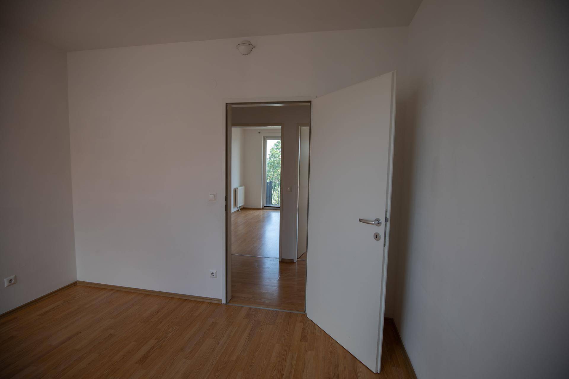 Leeres Zimmer mit Holzboden und weiß gestrichenen Wänden, bereit zur individuellen Gestaltung.