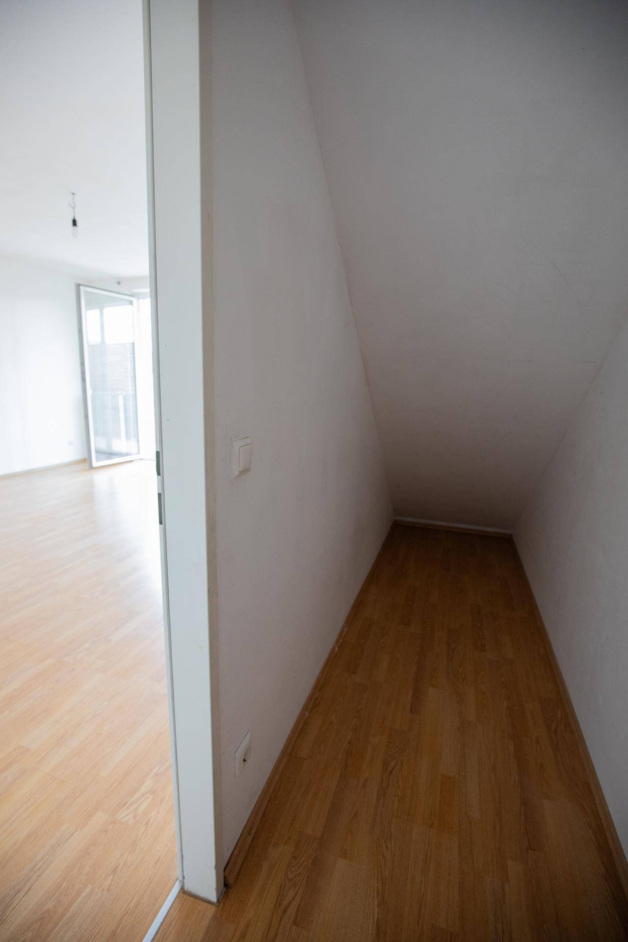 Abstellraum mit schräger Decke und Holzboden, ideal für zusätzlichen Stauraum.