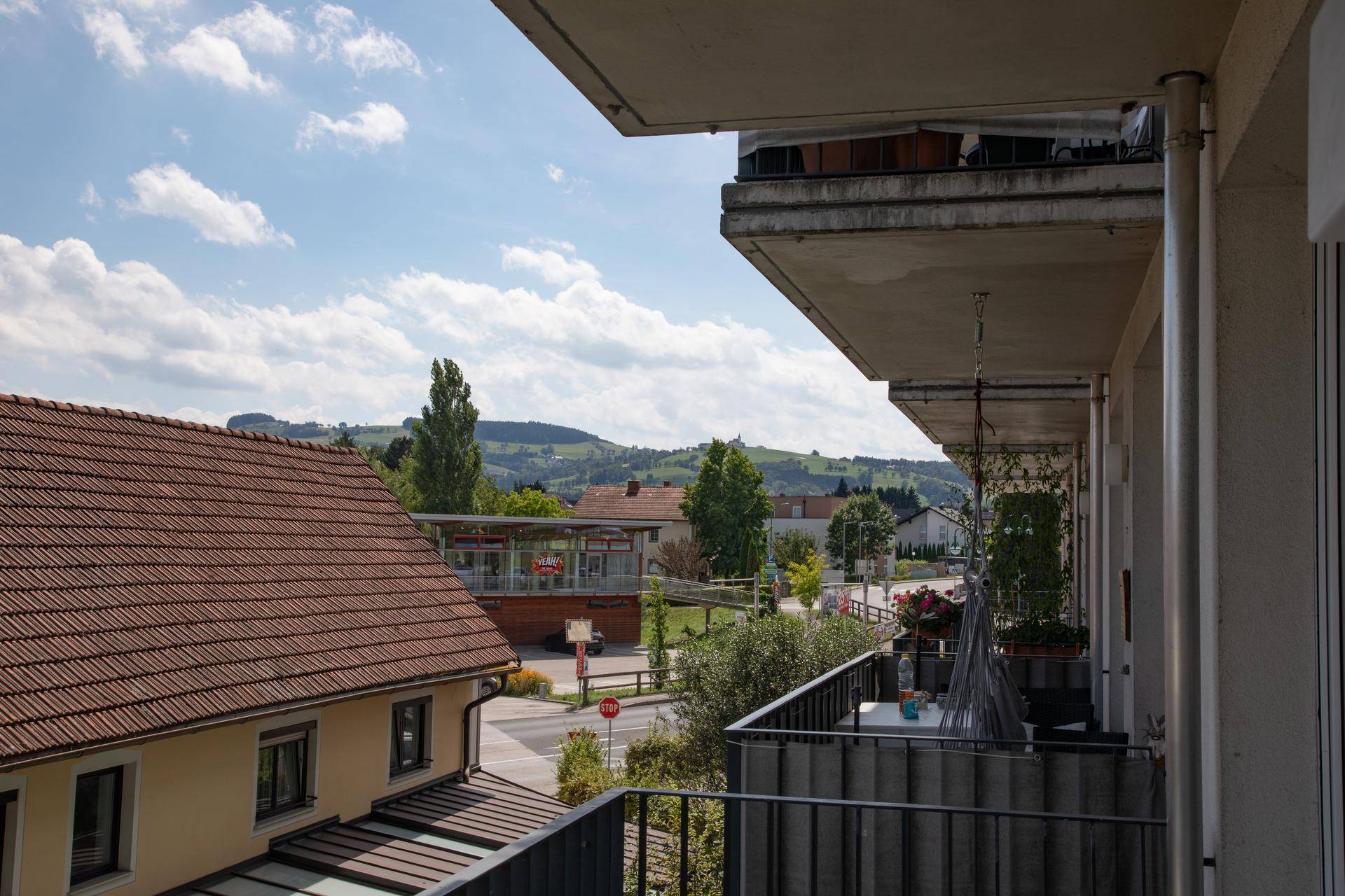 Balkon mit weitem Blick über die Straße und die umliegende grüne Landschaft.