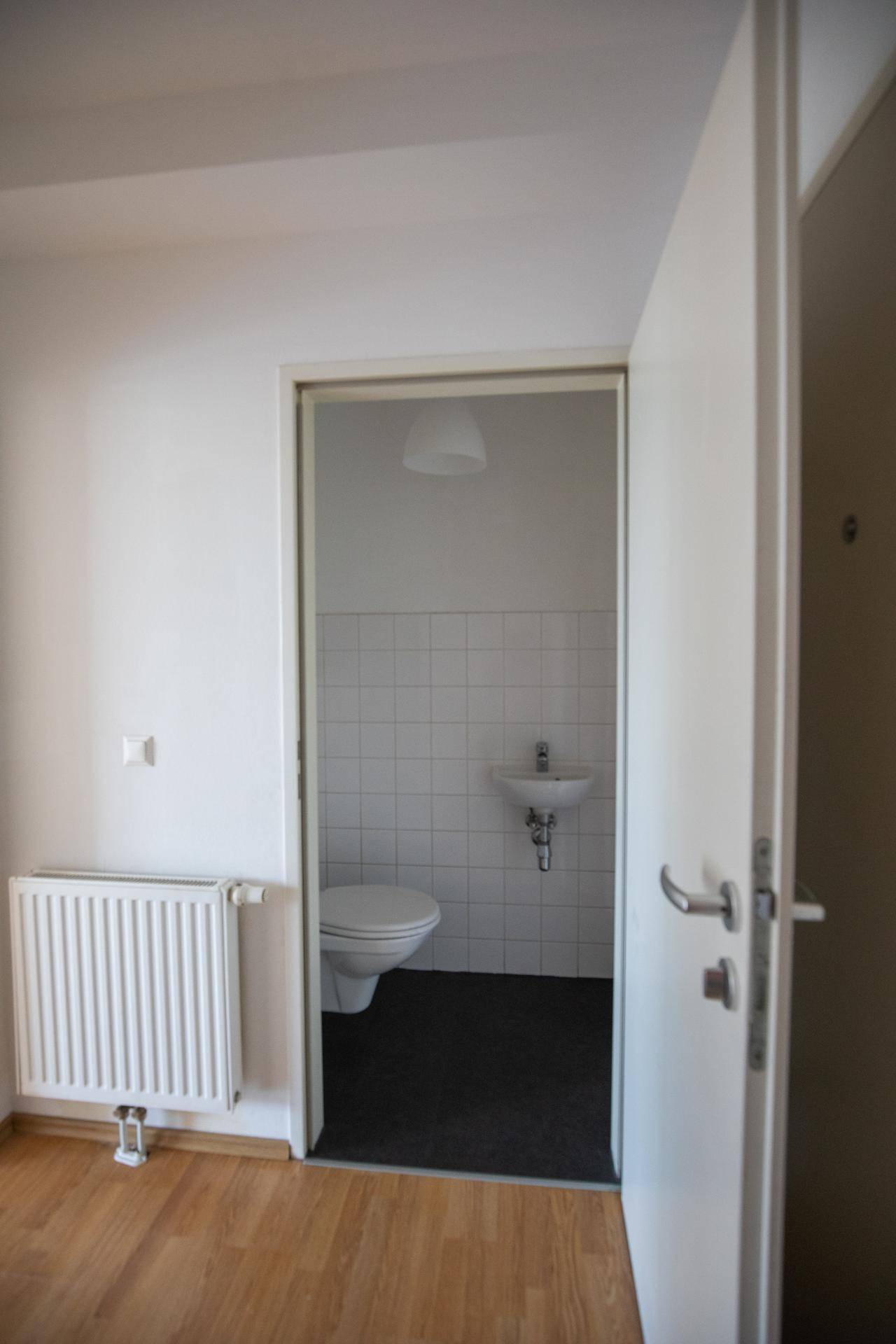 Kleines Gäste-WC mit Toilette, Waschbecken und weißen Fliesen.