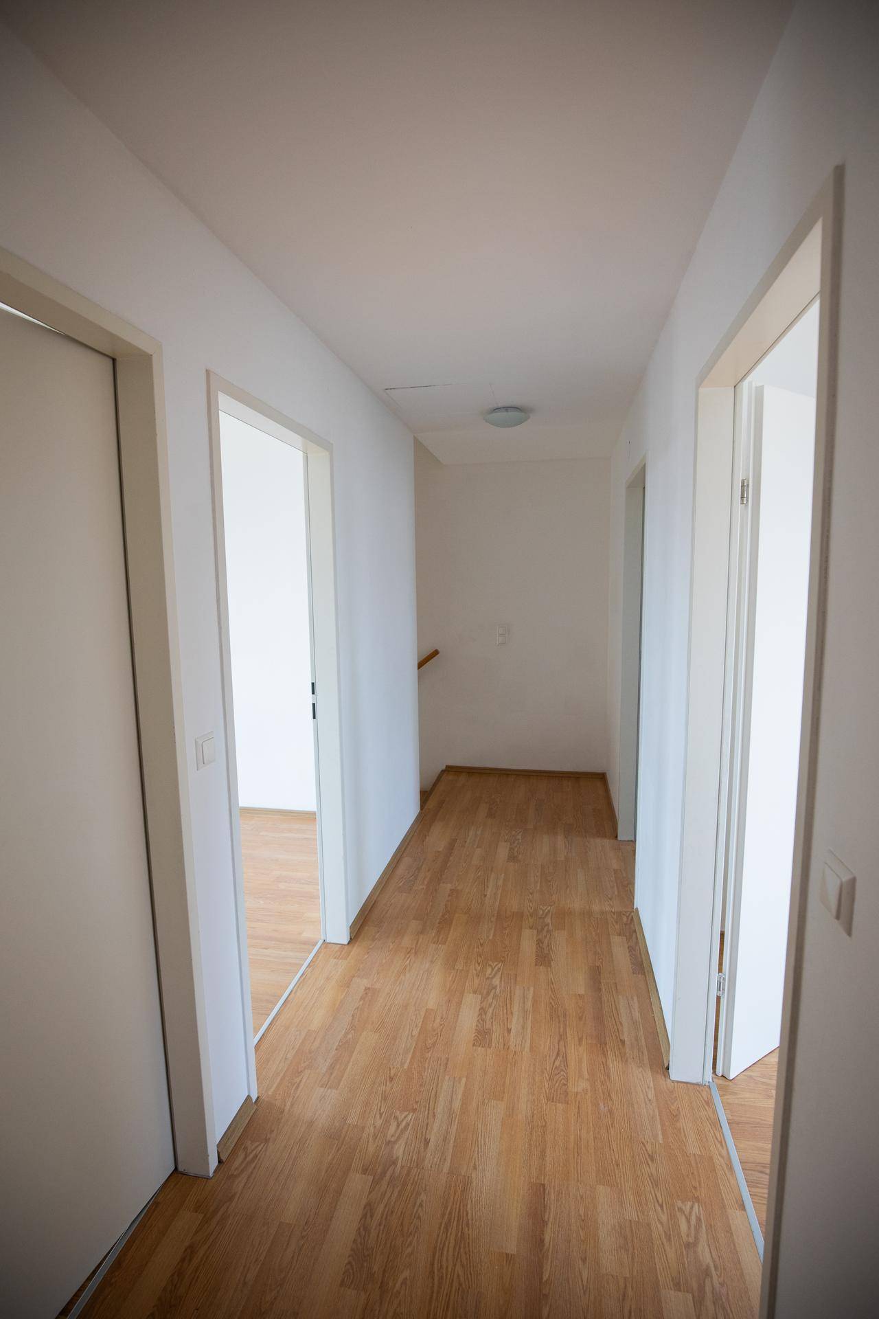 Heller Flur mit Holzboden und mehreren Türen, die zu den einzelnen Zimmern führen.